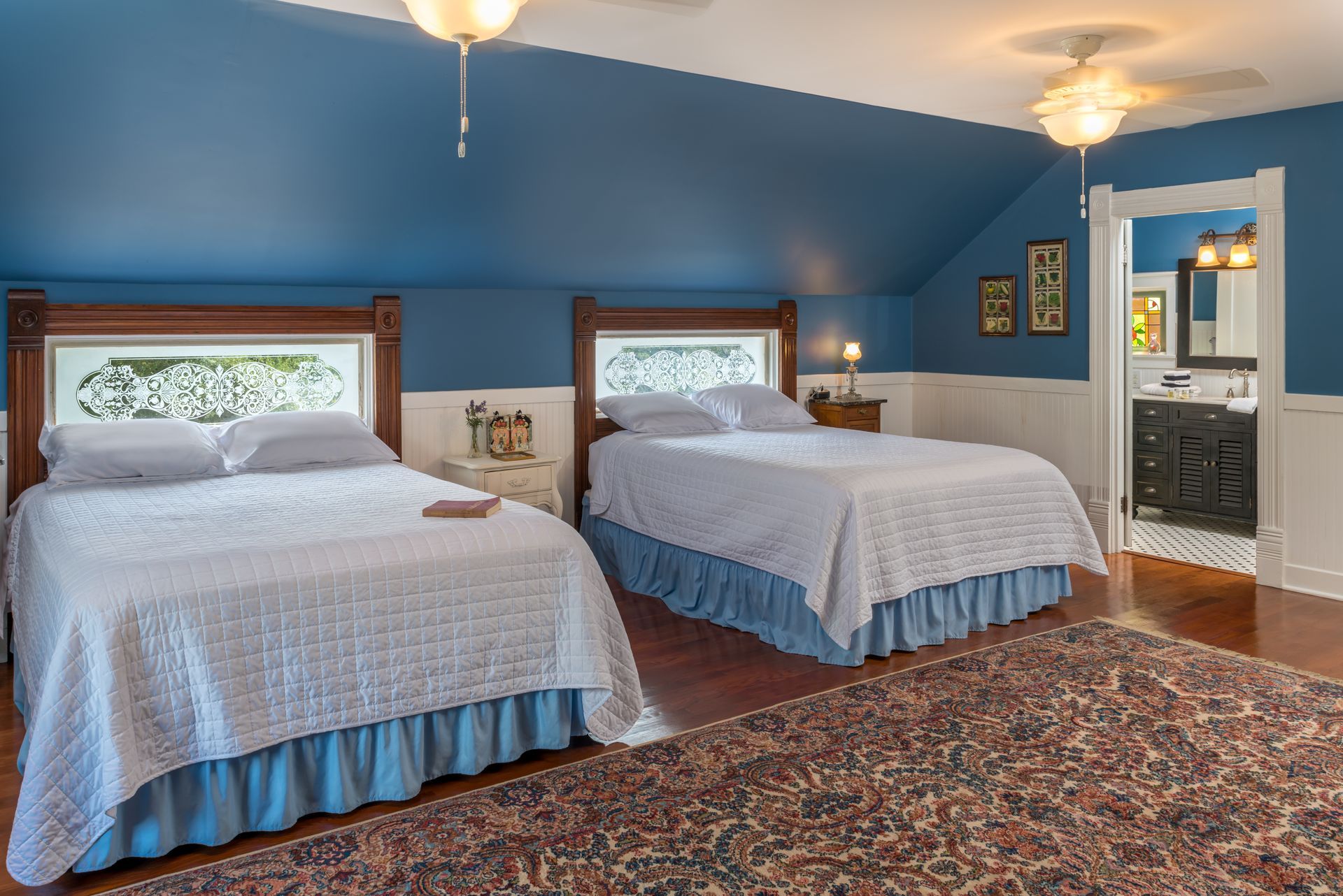 There are two beds in the room with blue walls.