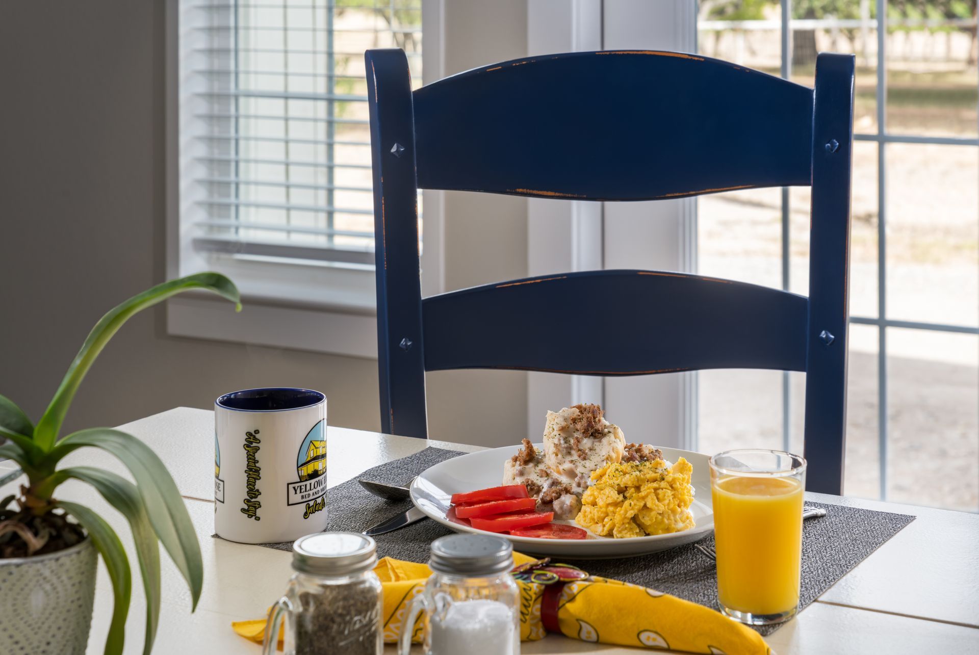 A table with a plate of food and a glass of orange juice on it.