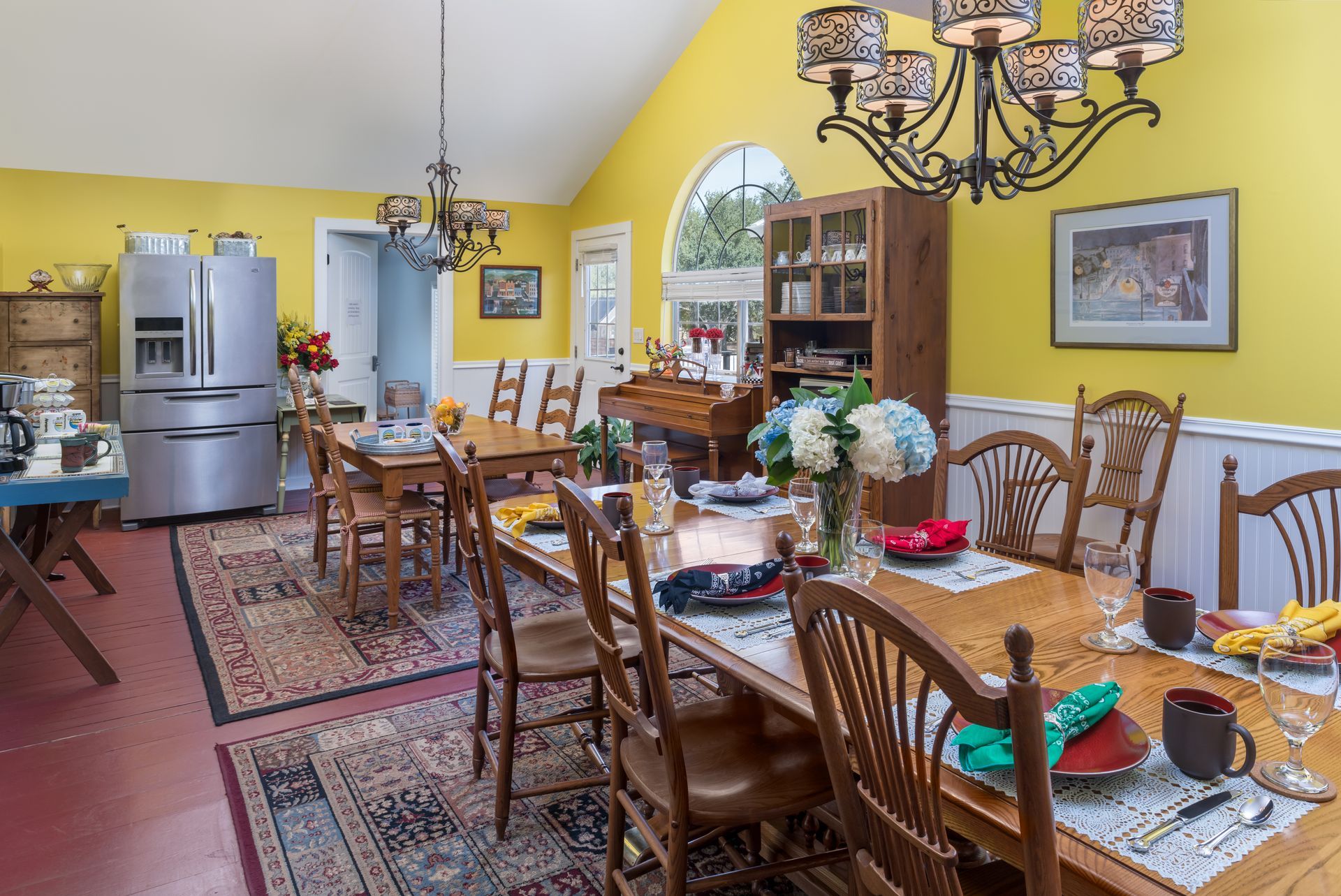 A dining room with a long table and chairs and a chandelier.