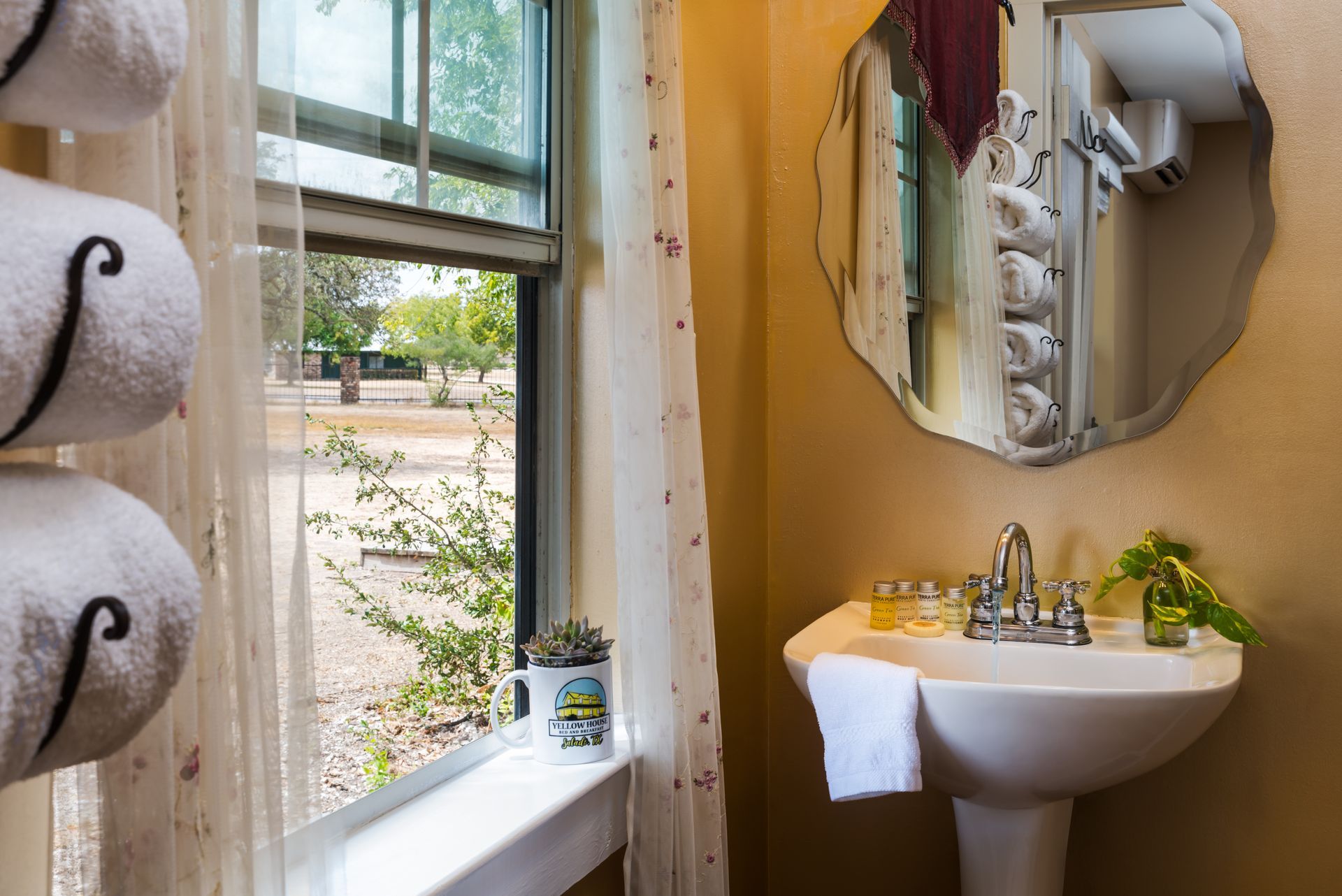 A bathroom with a sink , mirror and window.