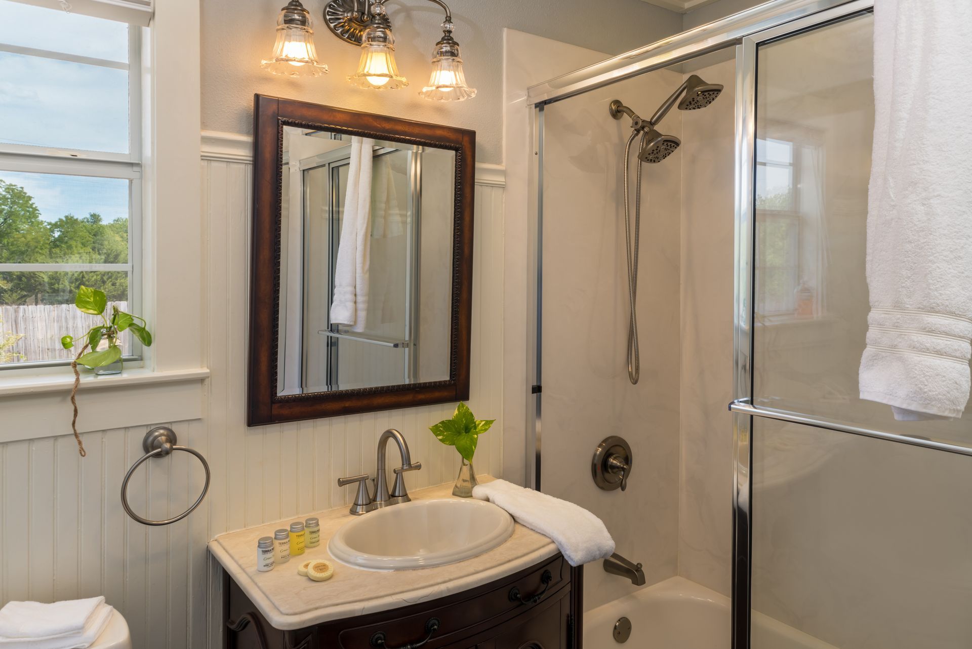 A bathroom with a sink , mirror , tub and shower.