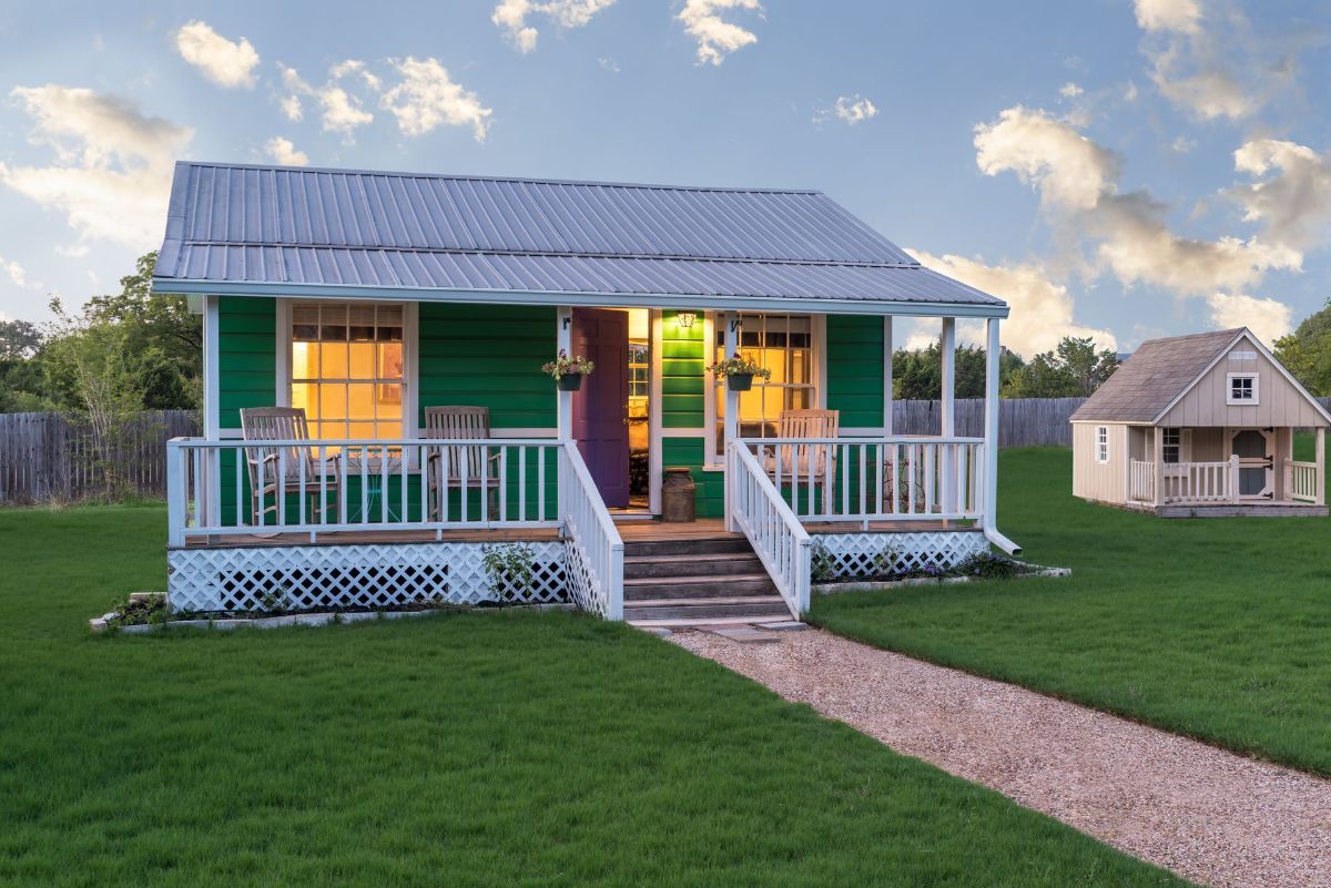A green and white house with a porch and stairs