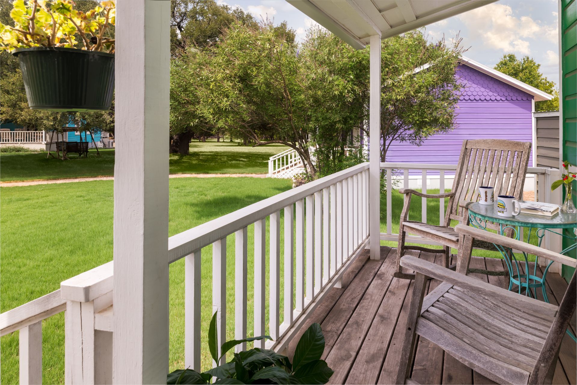 A porch with a table and chairs and a purple house in the background.