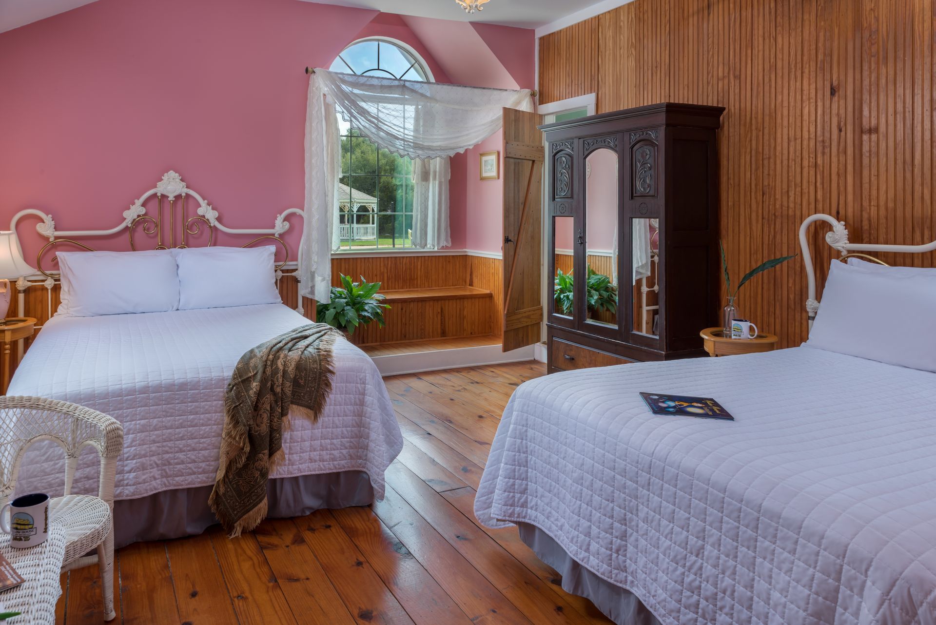 A bedroom with two beds , a chair and a wardrobe.