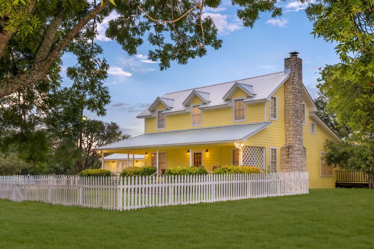A yellow house with a white picket fence around it