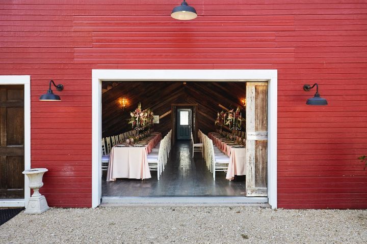 A red barn with a long table and chairs inside of it.