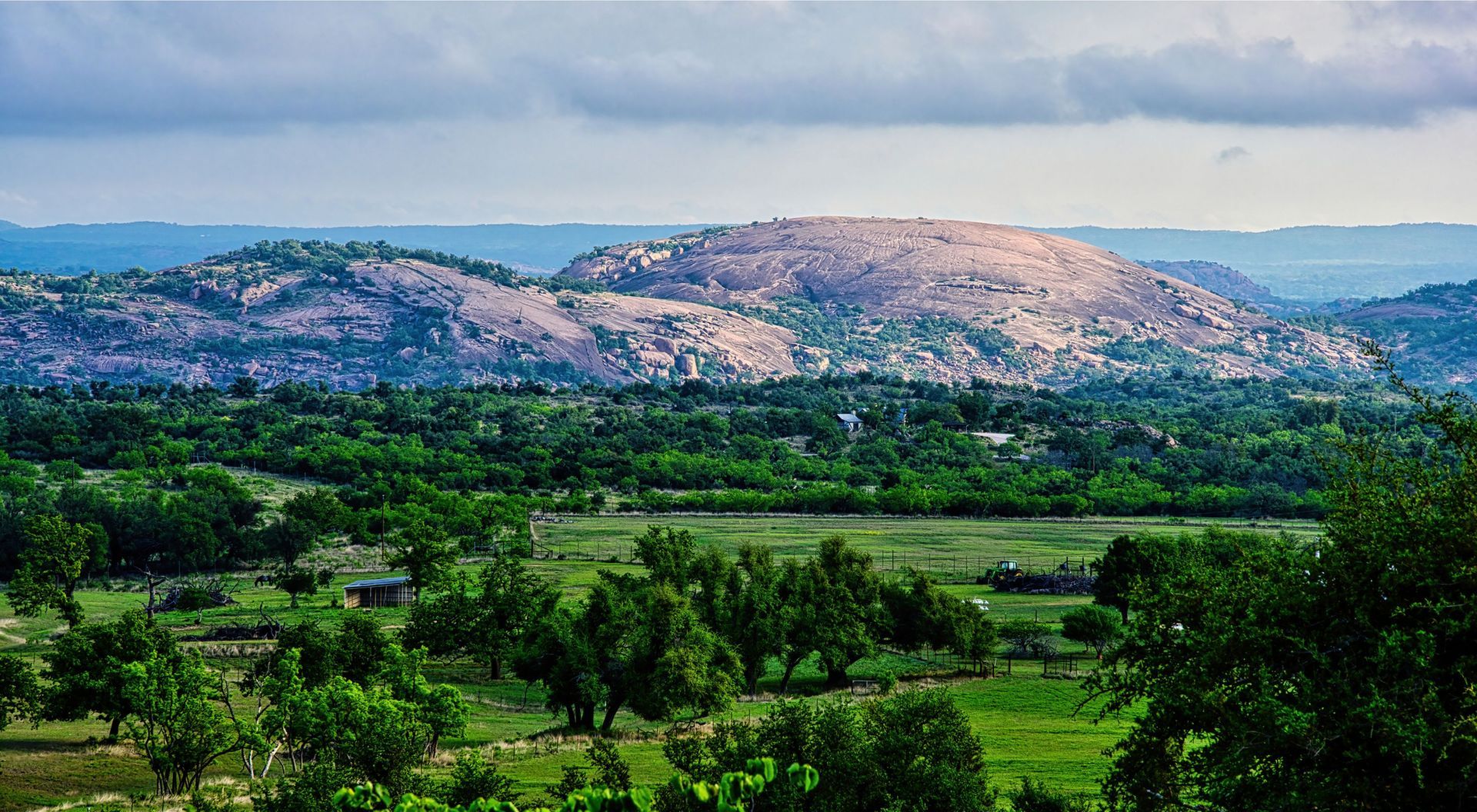 A view of a lush green valley with mountains in the background.
