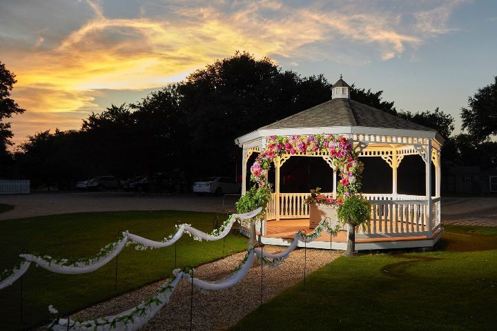 A gazebo decorated with flowers and ribbons is lit up at night.