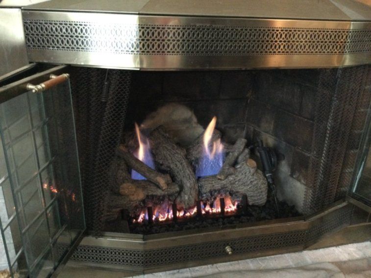 A fireplace with a stainless steel hood and a glass door.