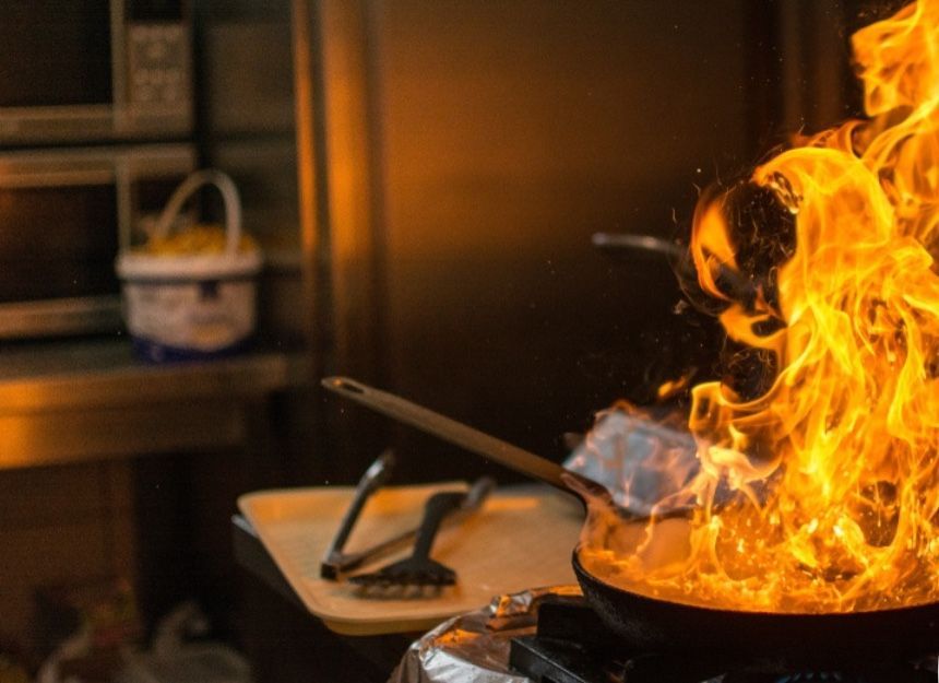 A pan is cooking on a stove with flames coming out of it.