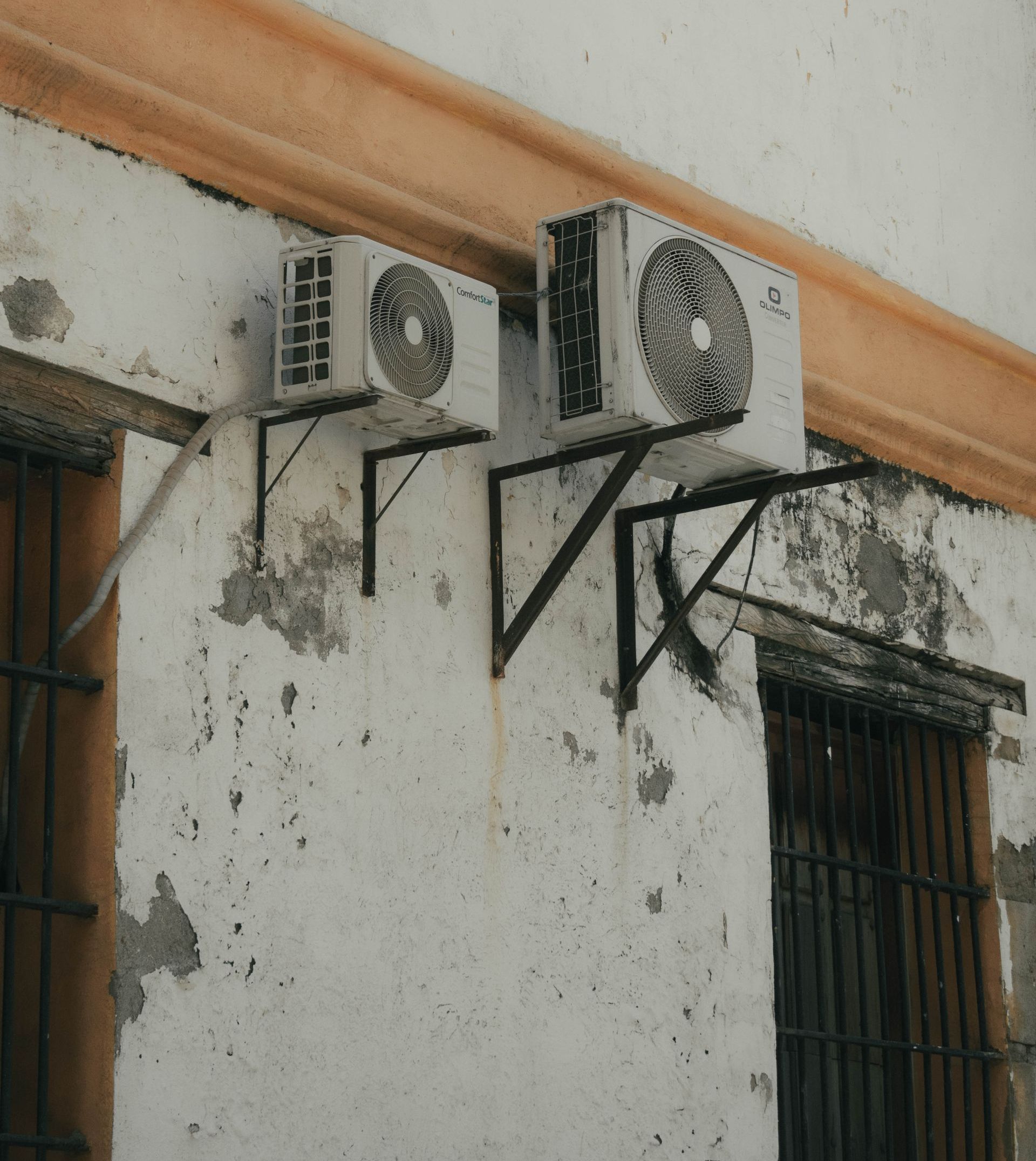 Two air conditioners are mounted on the side of a building