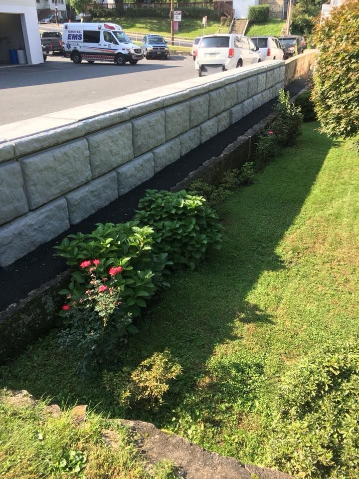 Stone retaining wall installation along roadside