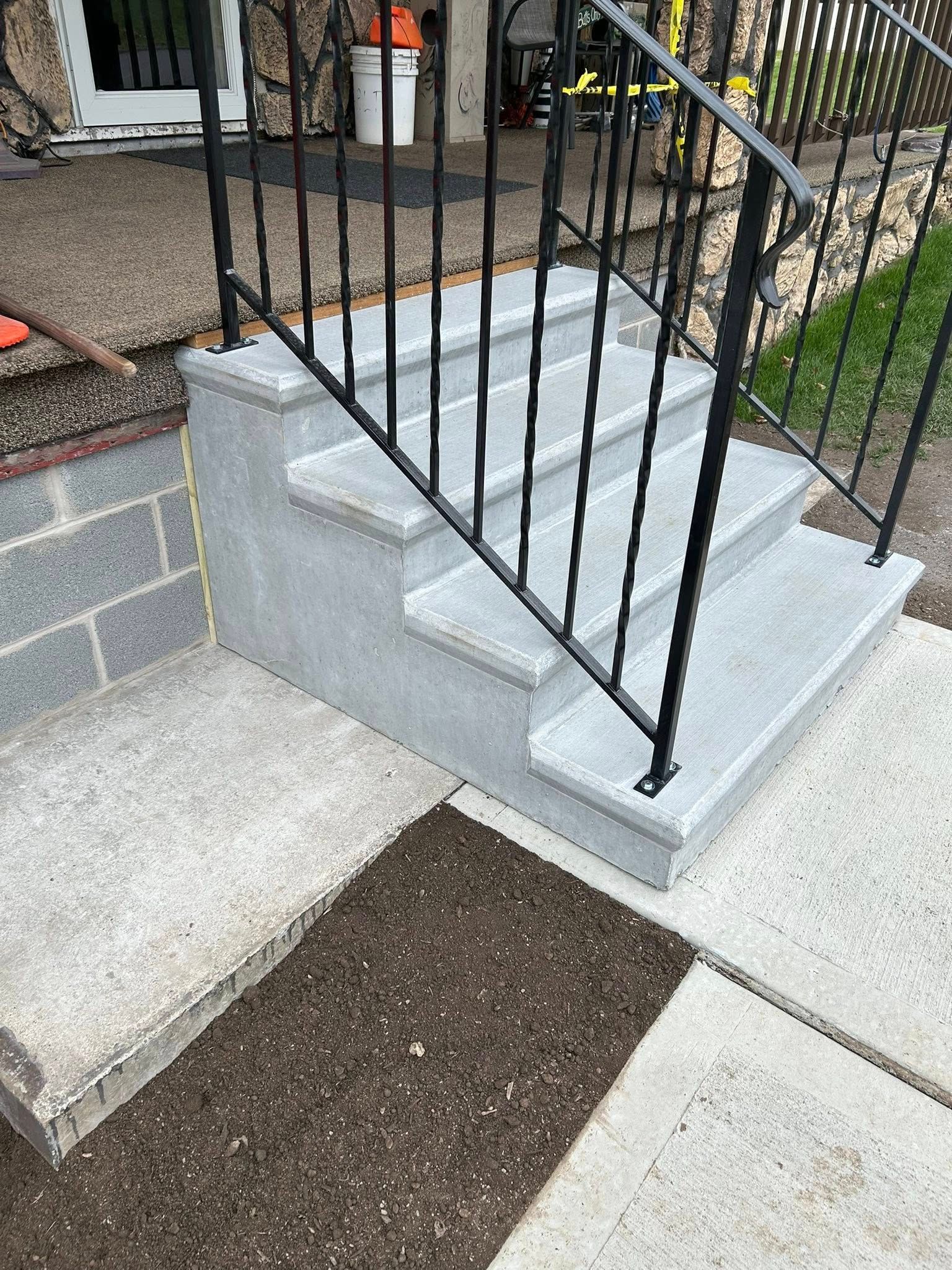 Concrete step and landing installation with metal railing