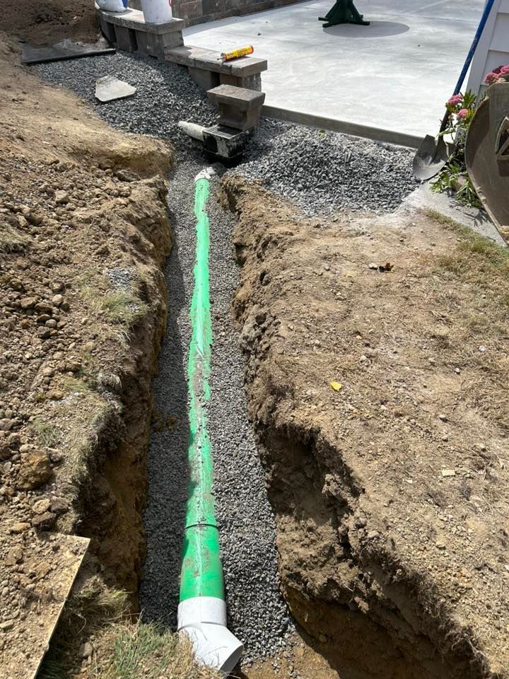 Excavated trench with pipe placement near concrete slab