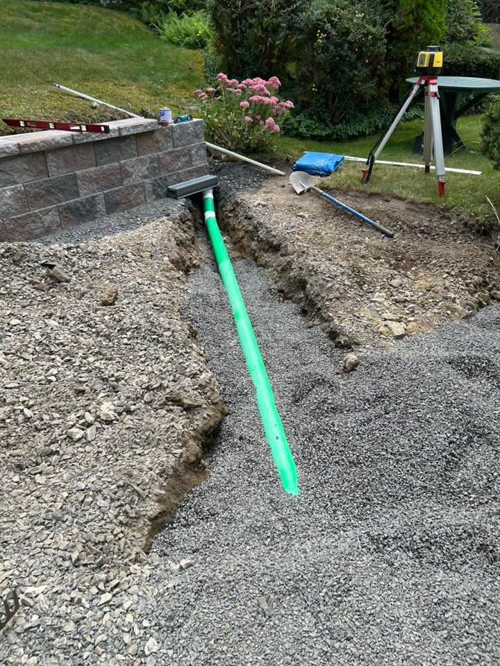 Retaining wall construction with drainage pipe installation