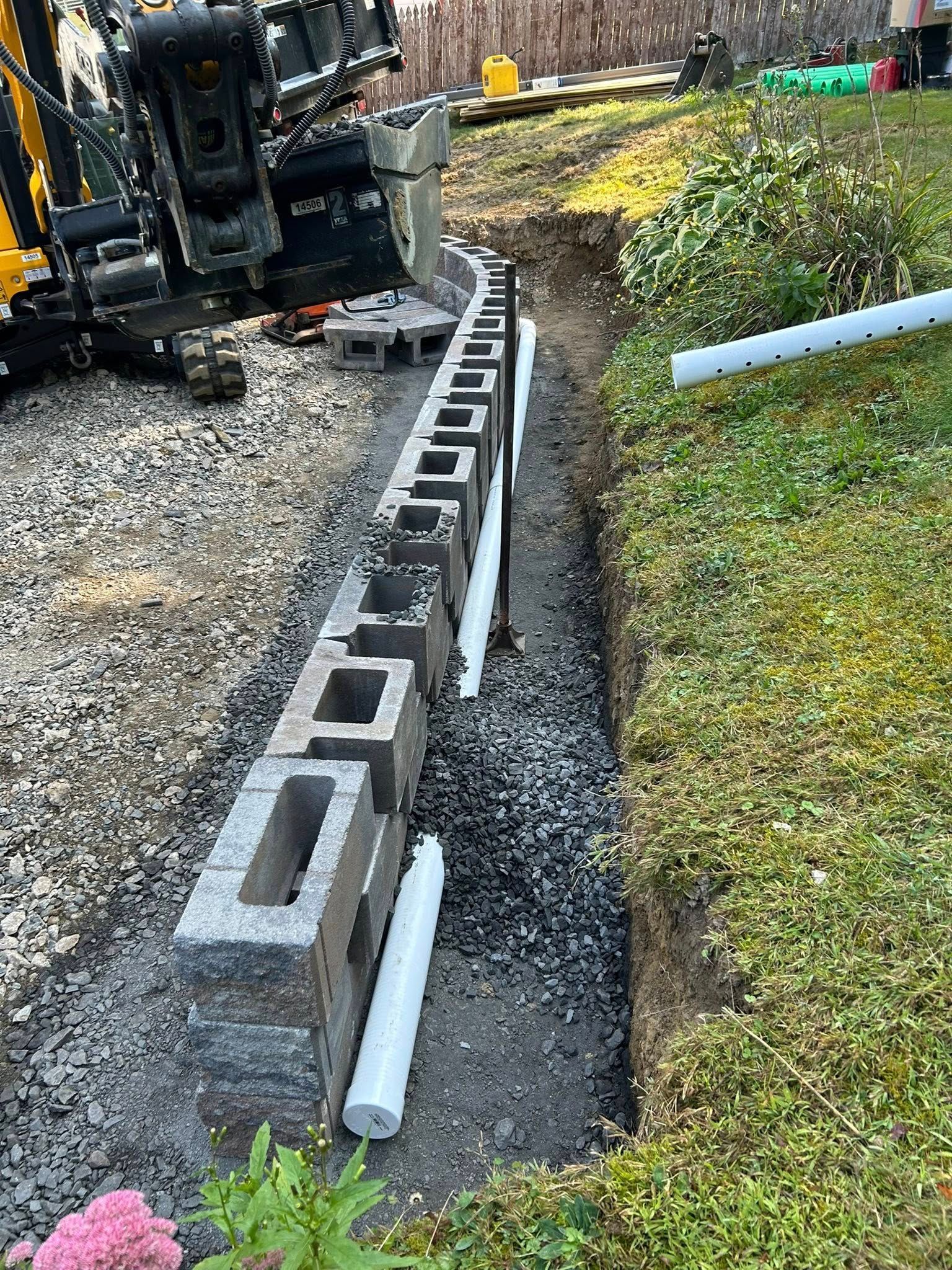 Retaining wall block installation with excavation equipment
