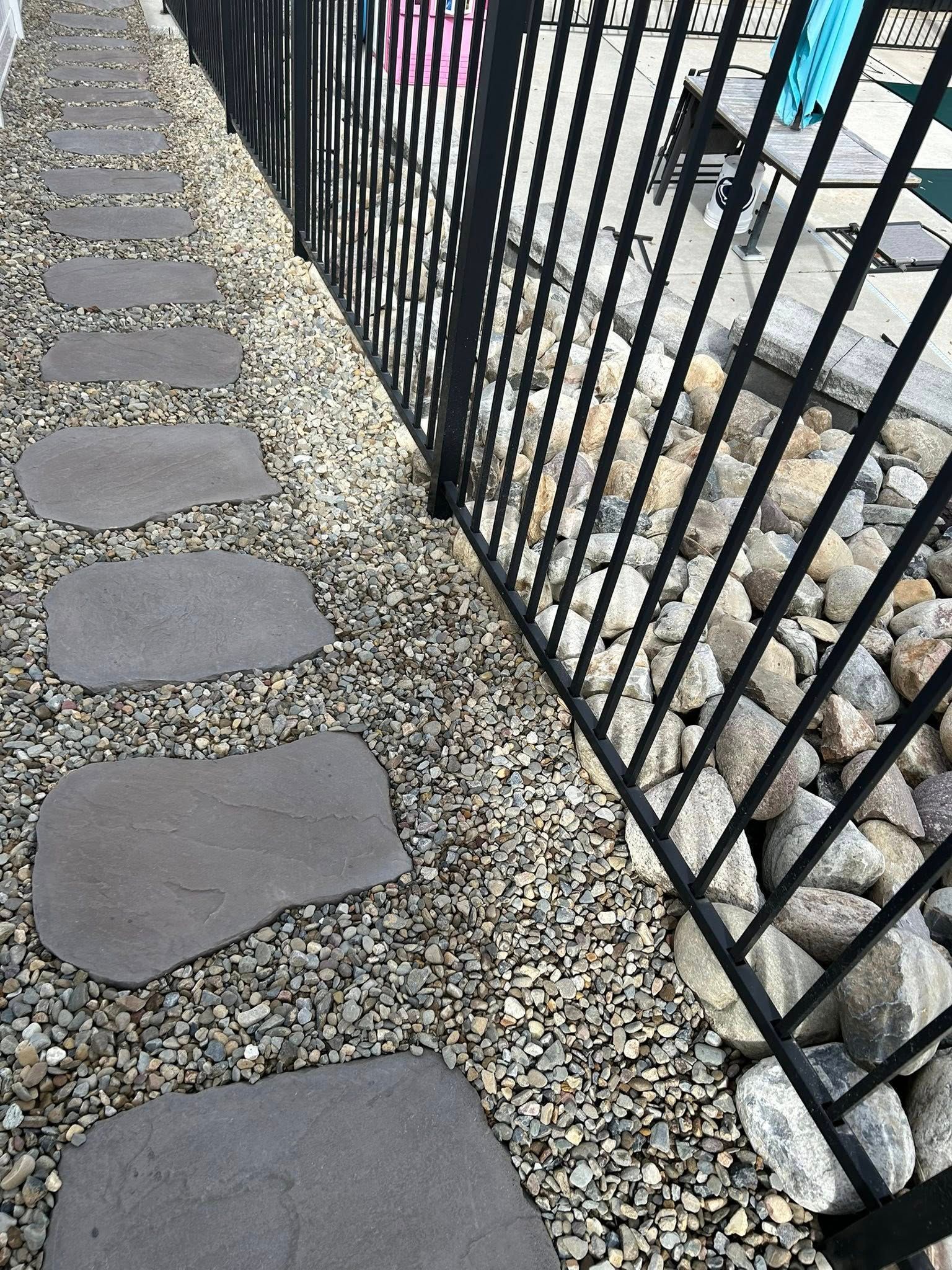 Stone walkway installation along fence line