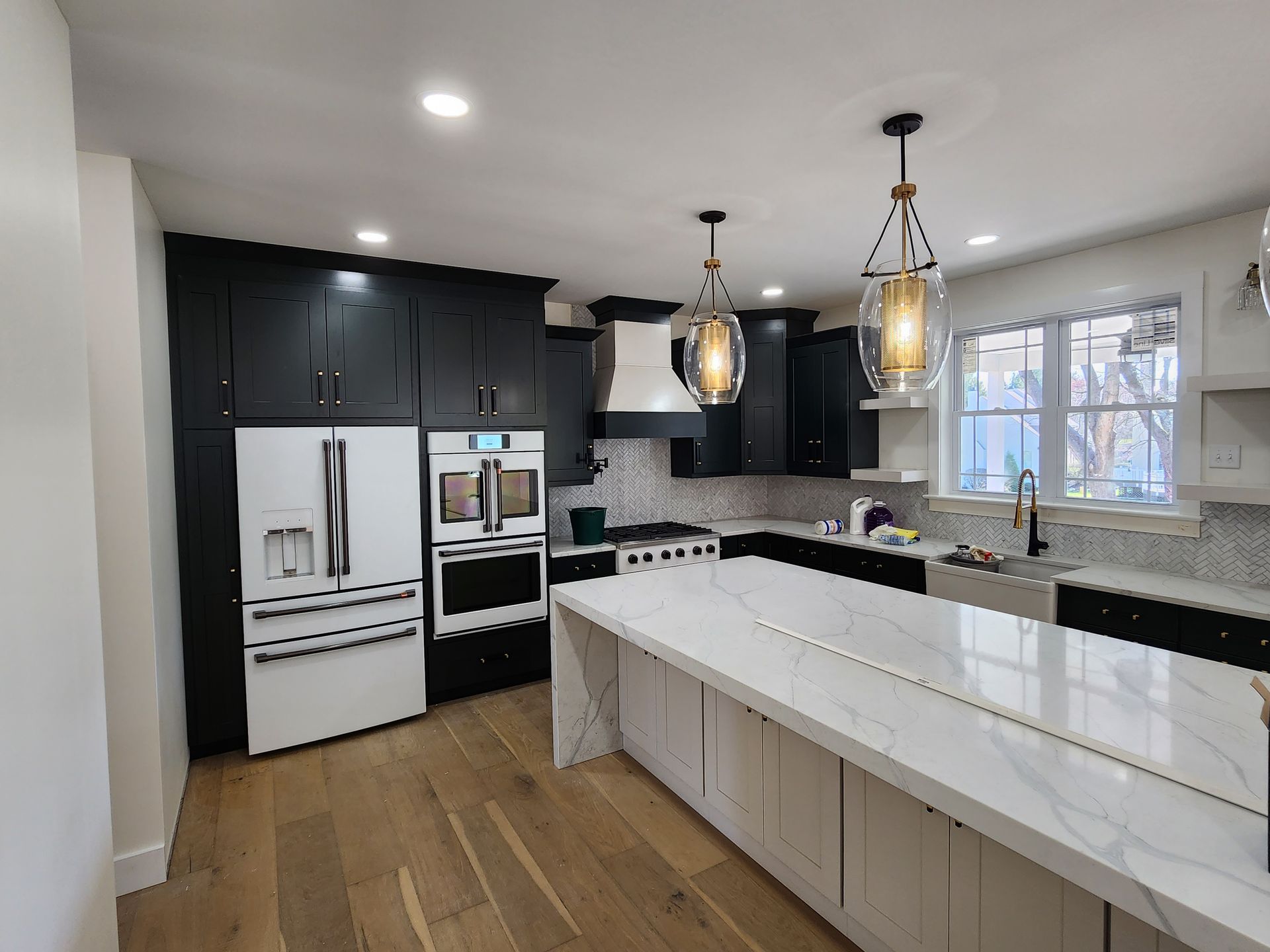 A kitchen with black cabinets and white counter tops and a large island.