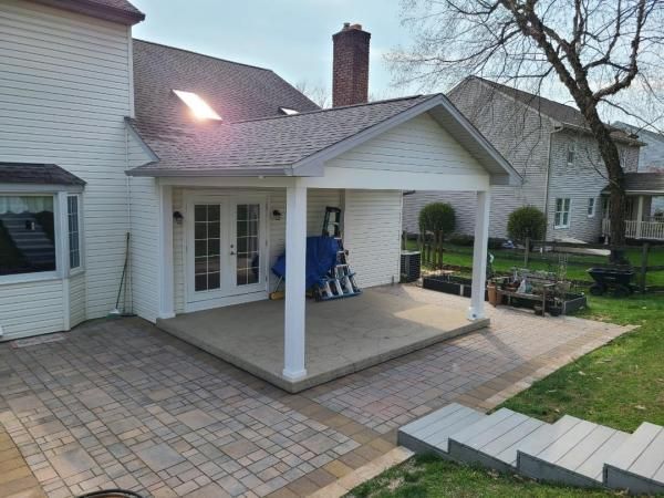 A white house with a porch and stairs in front of it.