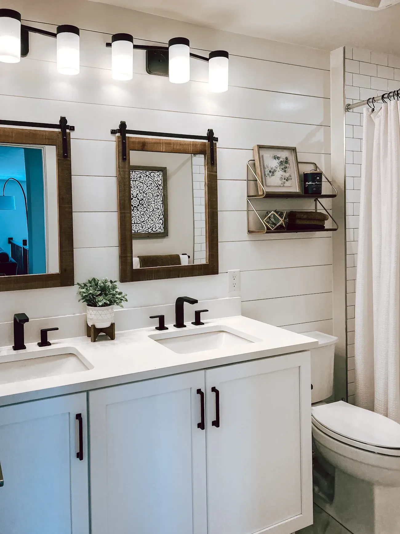A bathroom with two sinks , two mirrors , a toilet and a shower curtain.