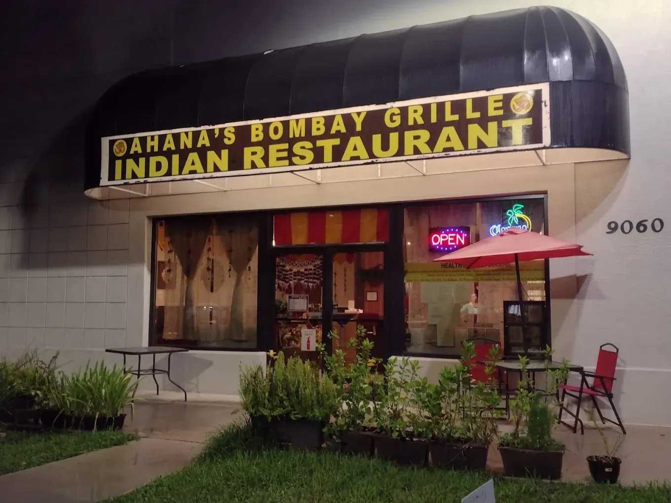 Oahana's Bombay Grille Indian restaurant with awning, open sign, small patio, and potted plants.