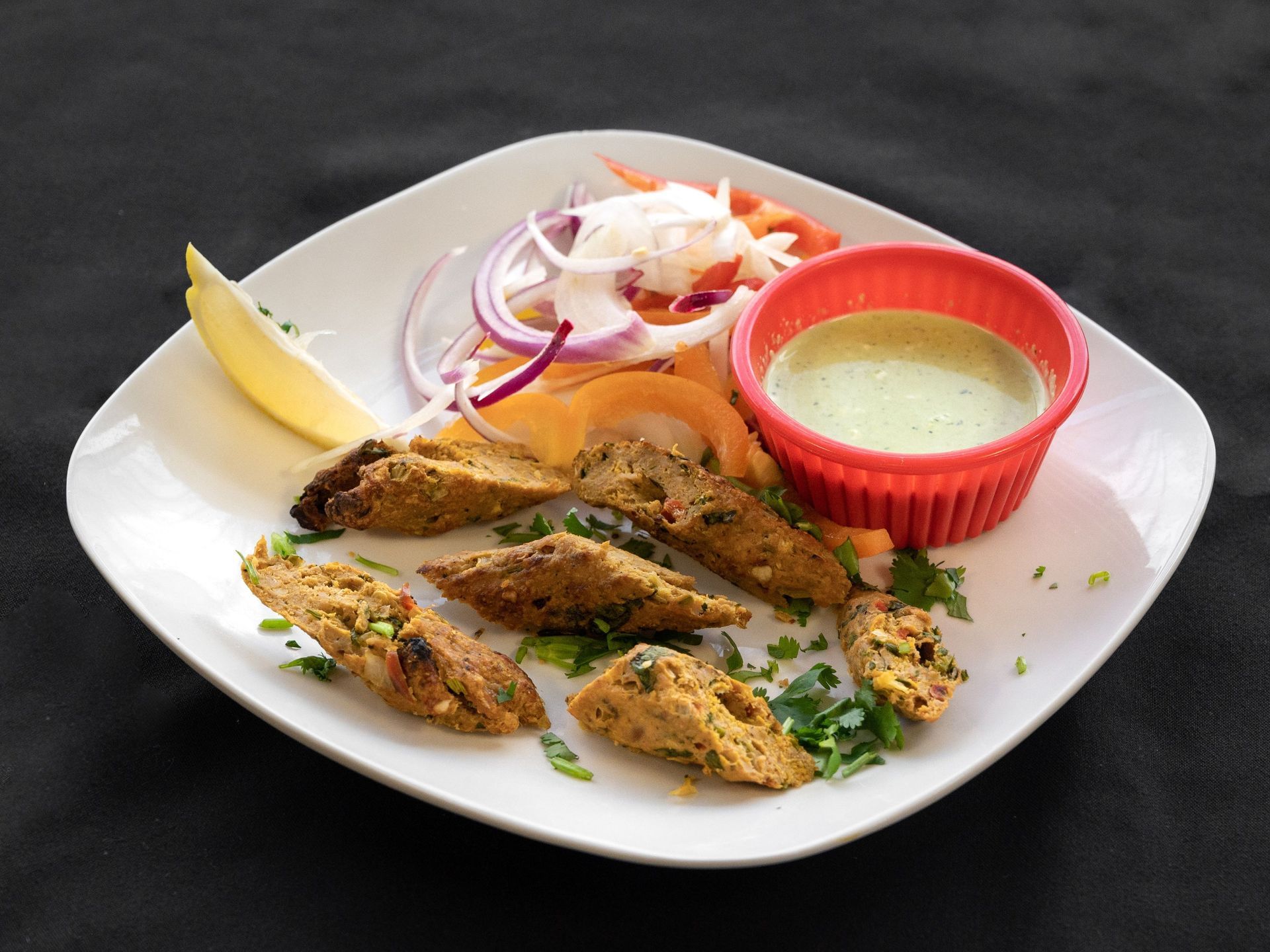 Plate of Indian kebabs with green sauce and salad.
