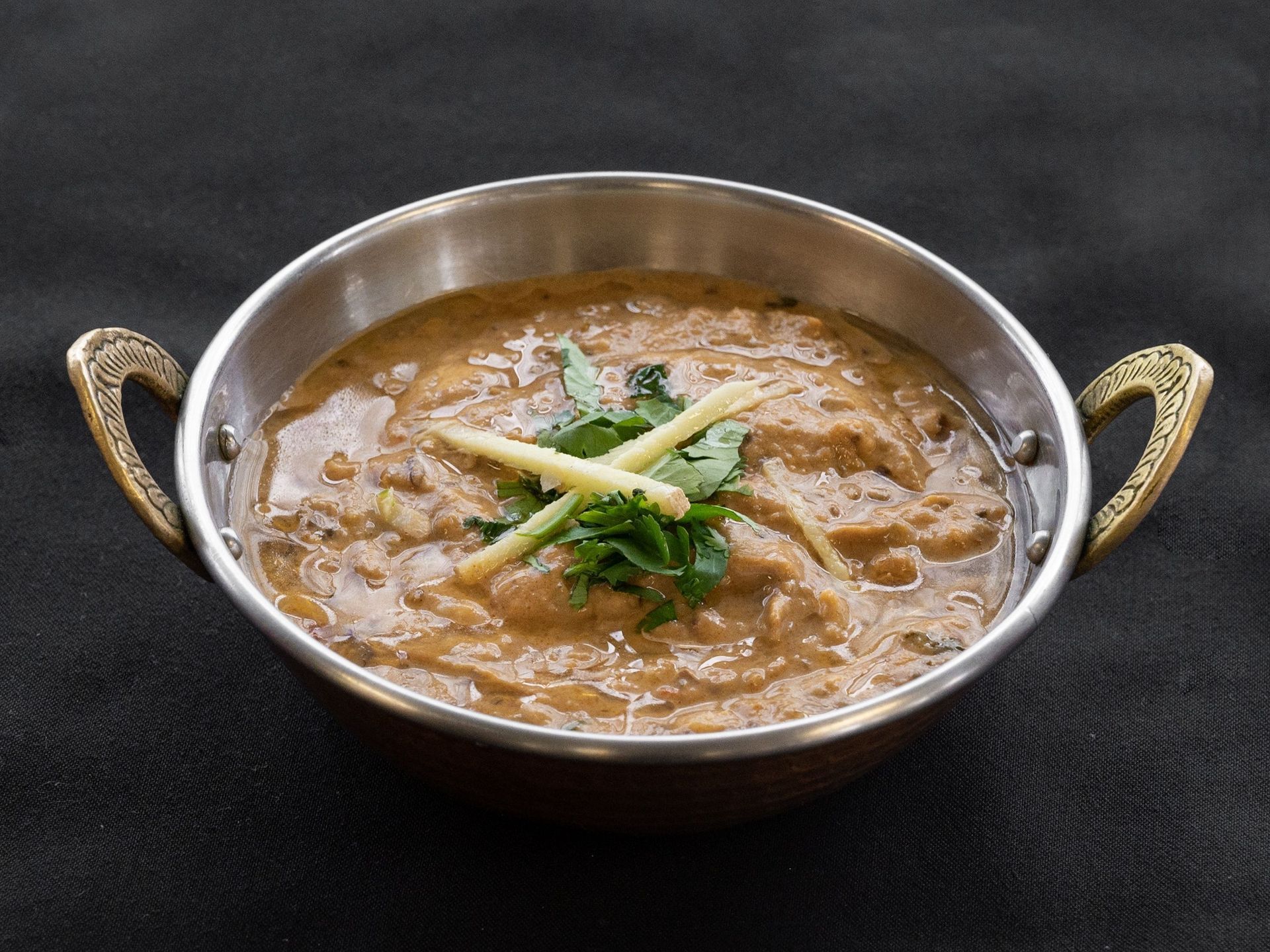 Bowl of creamy curry with ginger garnish.