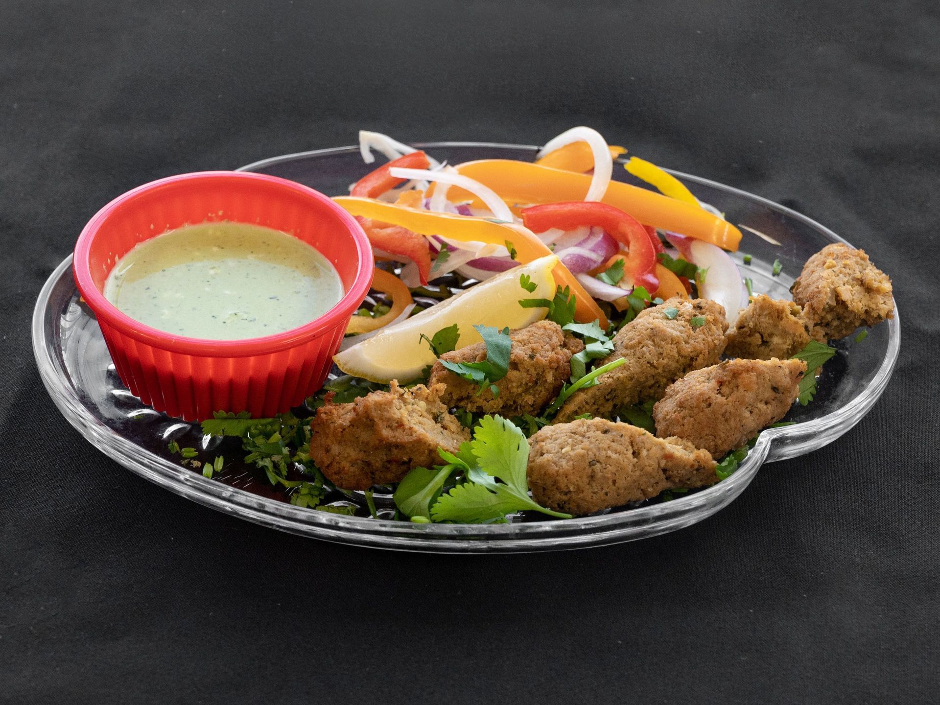 Kebabs with salad and green dipping sauce on a plate.