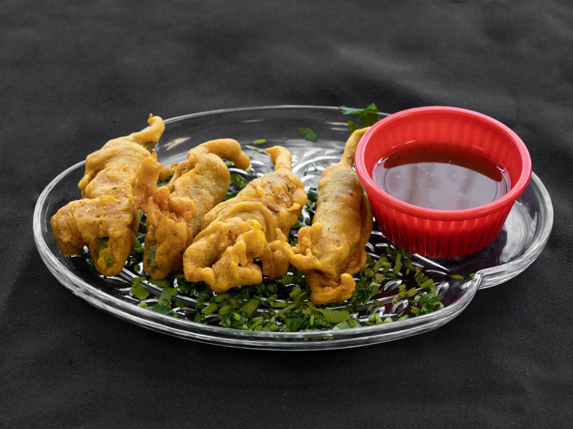 Fried peppers with dipping sauce on a clear plate.
