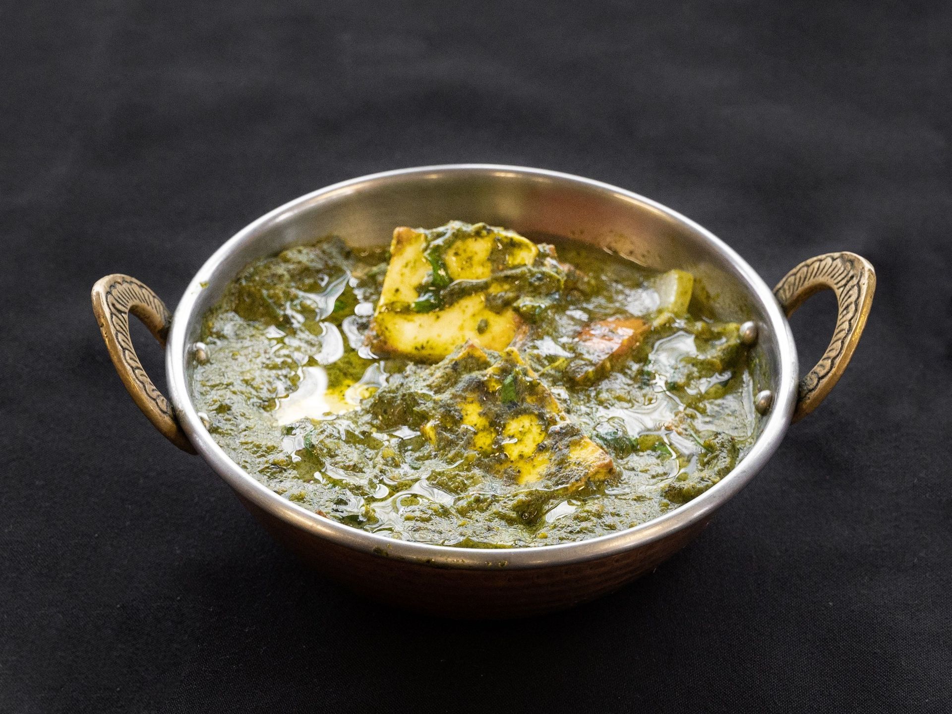 Palak Paneer, Indian spinach and cheese dish, in a decorative metal bowl.