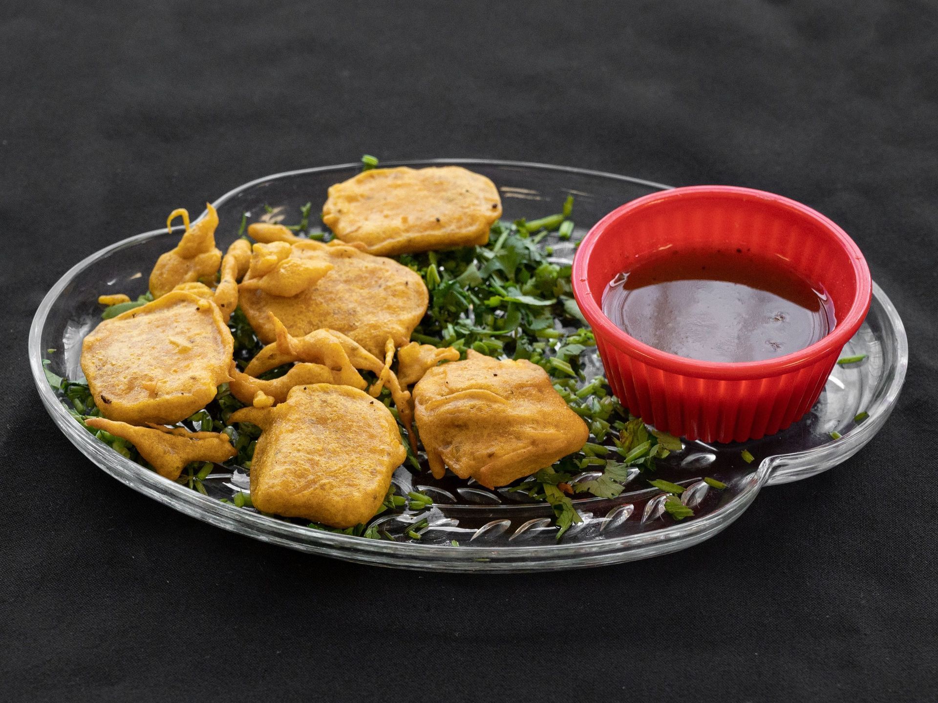 Fried food, chutney, and herbs on a plate.