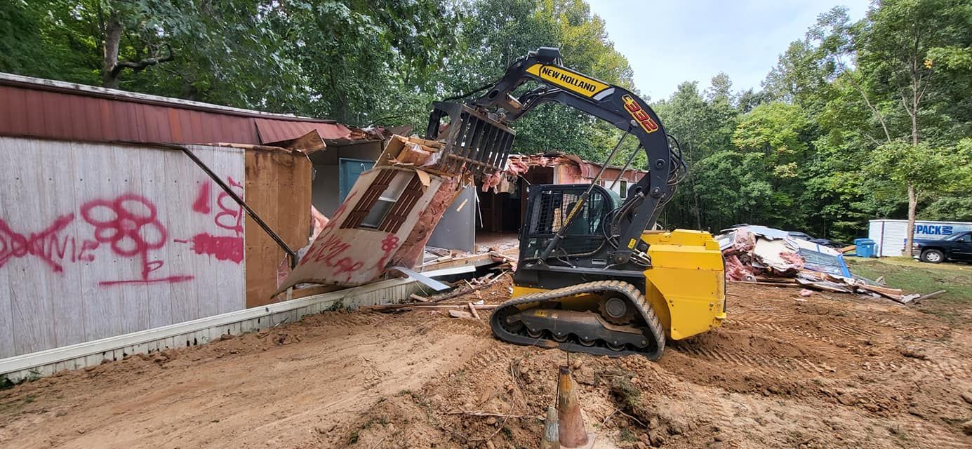 An excavator demolishes a building with graffiti on its wall.