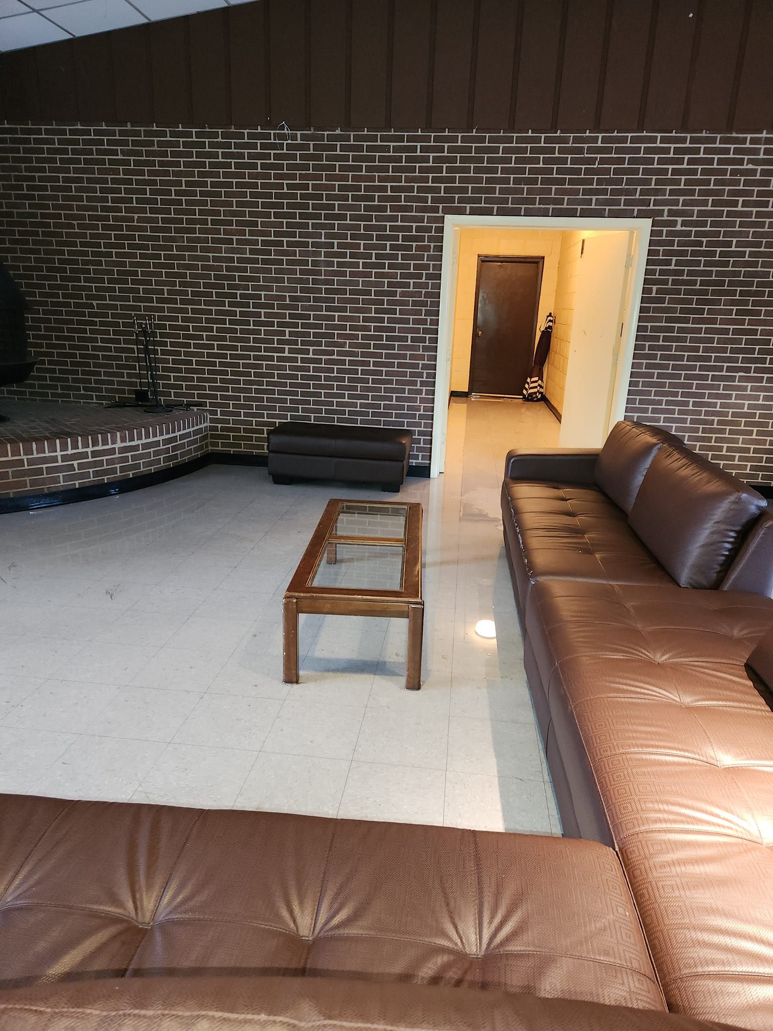 Brown leather sectional sofa in a living room with patterned wall and tile floor.