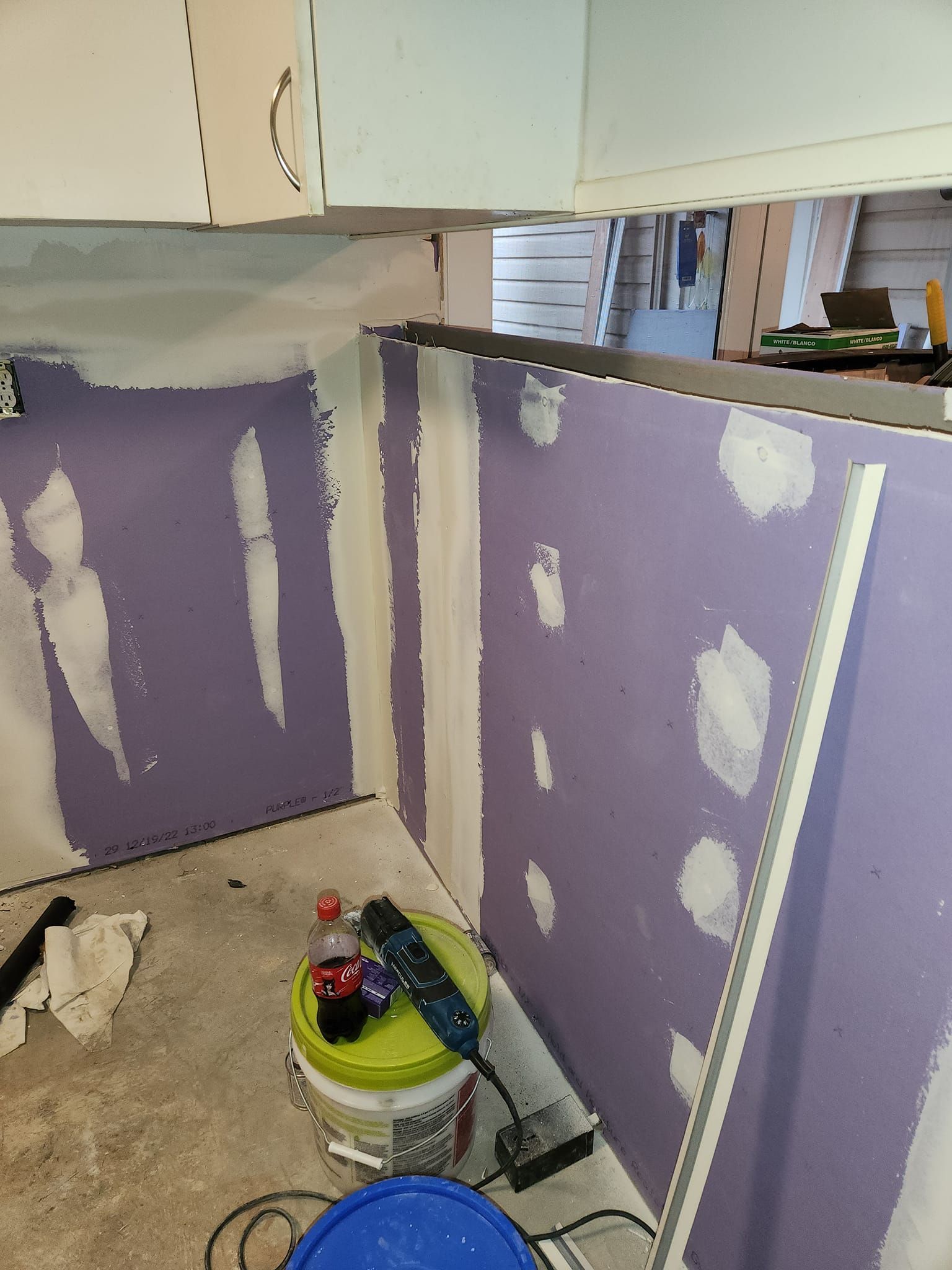 Interior view of a room under construction with purple drywall and partially finished walls.