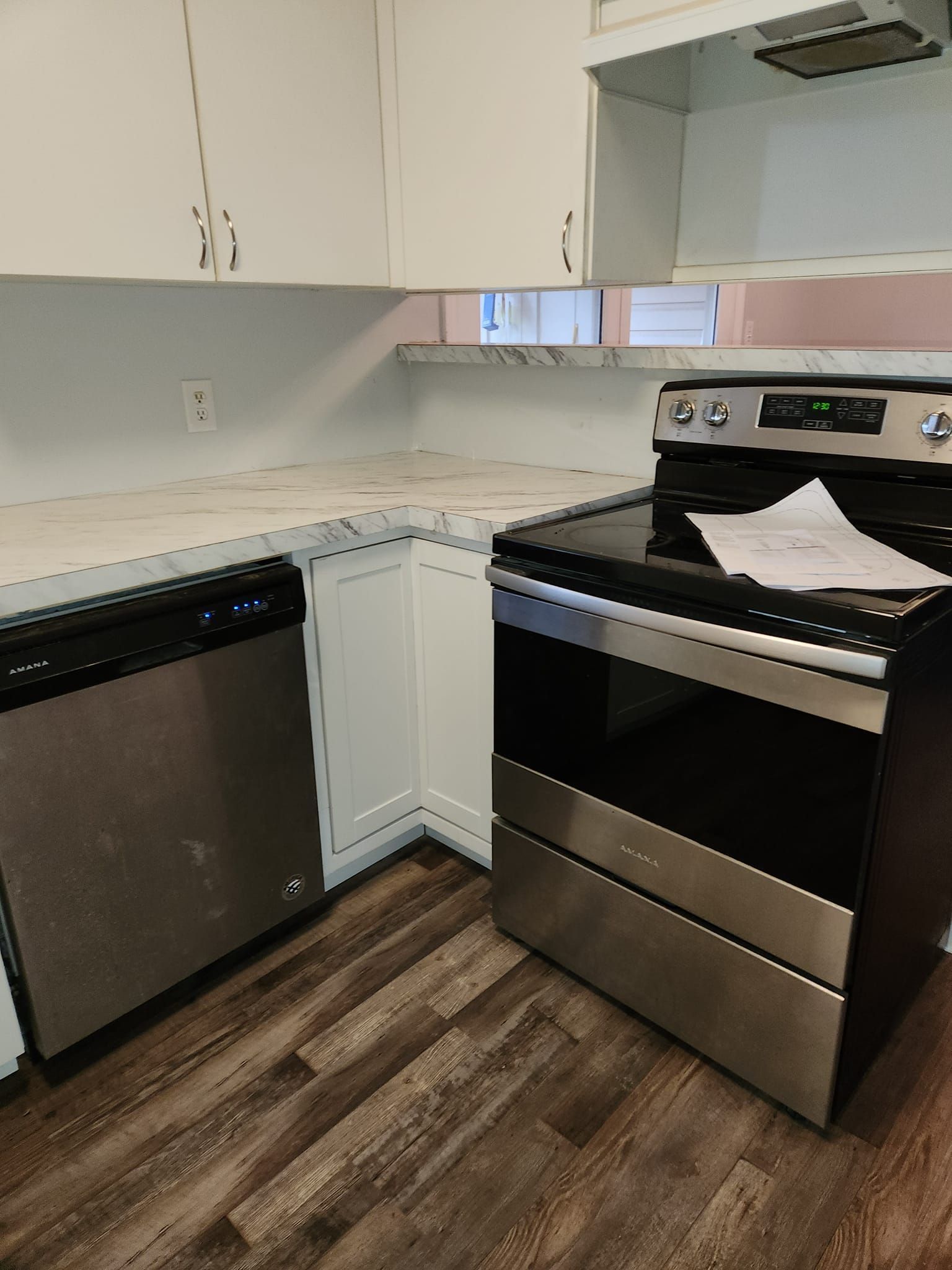 Kitchen with white cabinets, stainless steel appliances, and wood-look flooring.