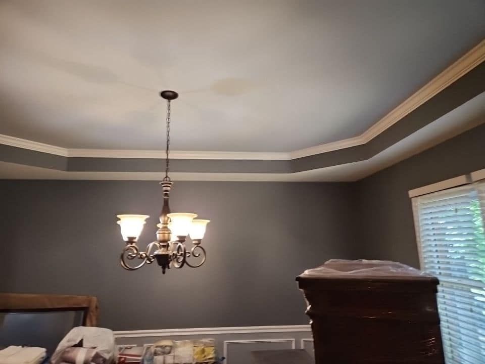 Gray dining room with chandelier, tray ceiling, and white trim.