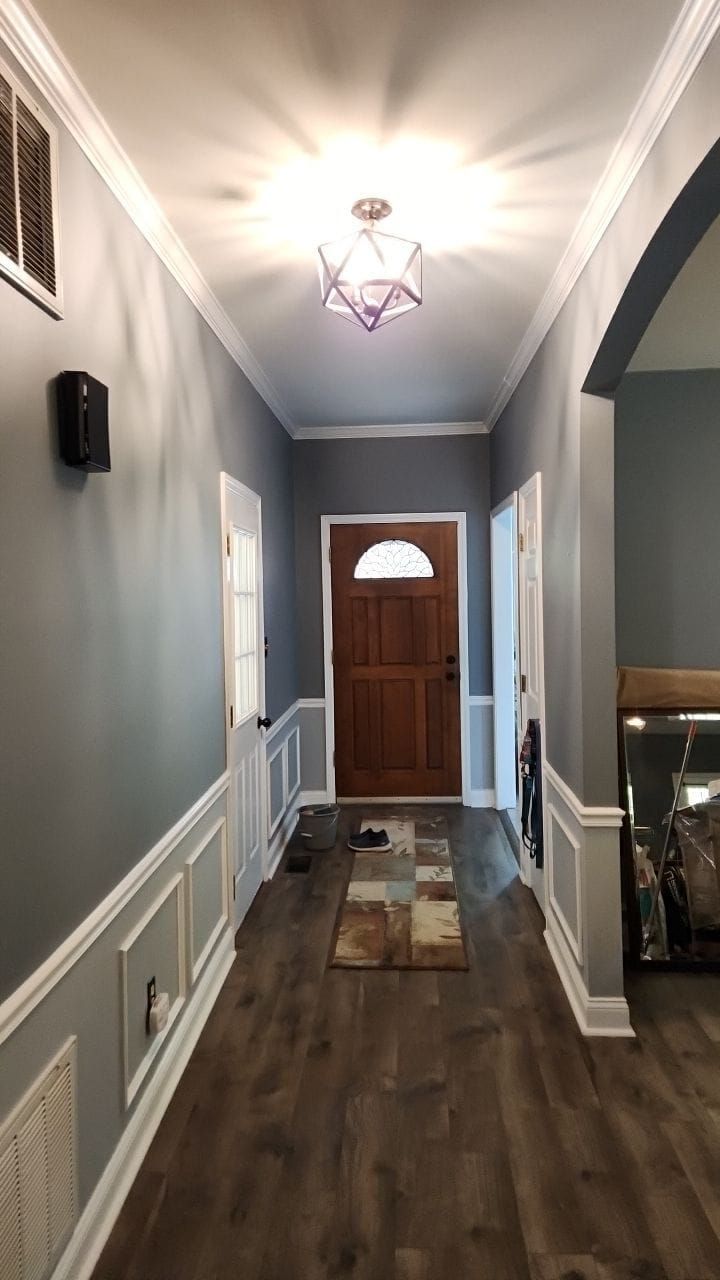 Long hallway with gray walls, white trim, and a wooden door.