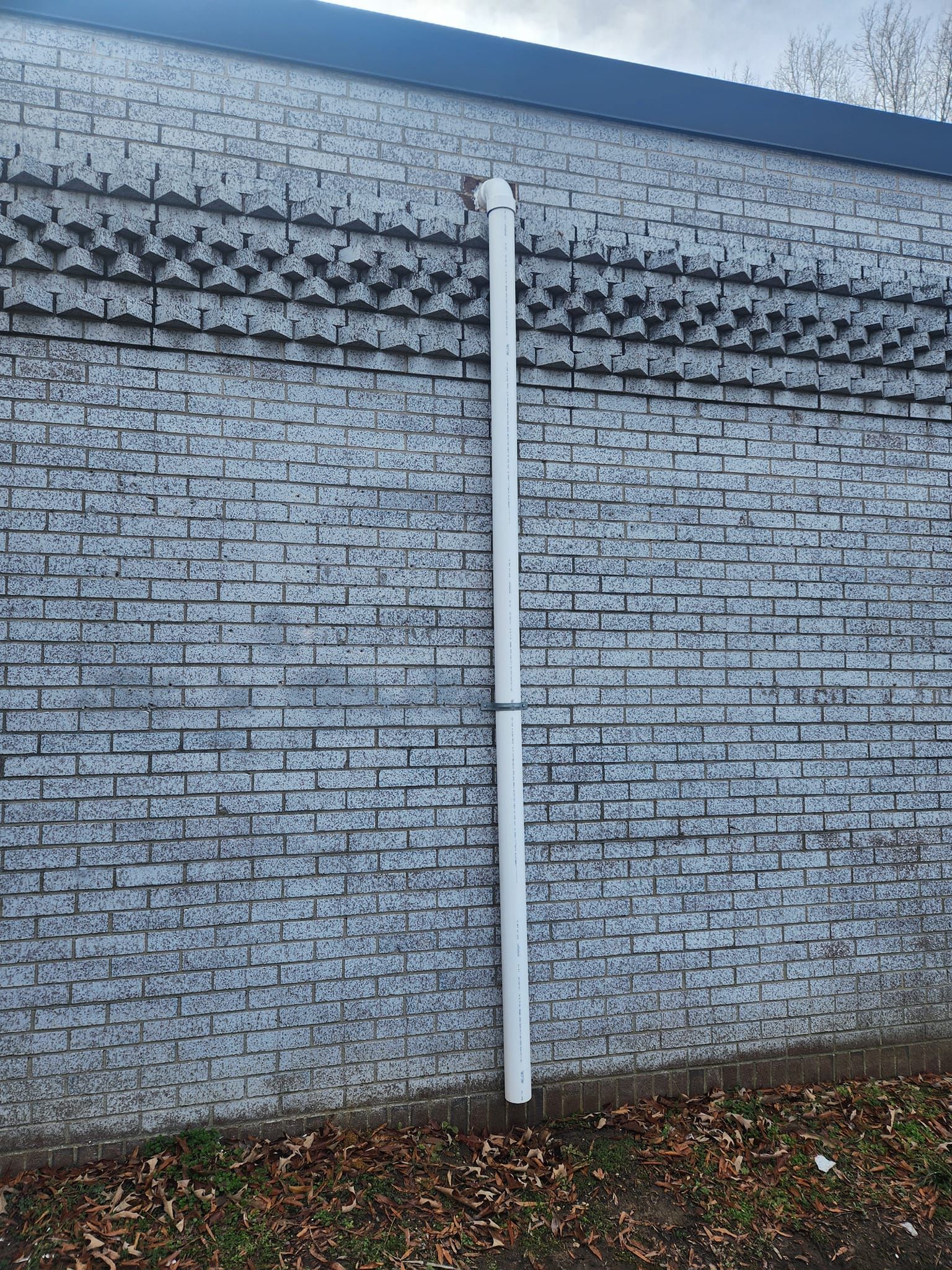 White downspout attached to a gray brick building.