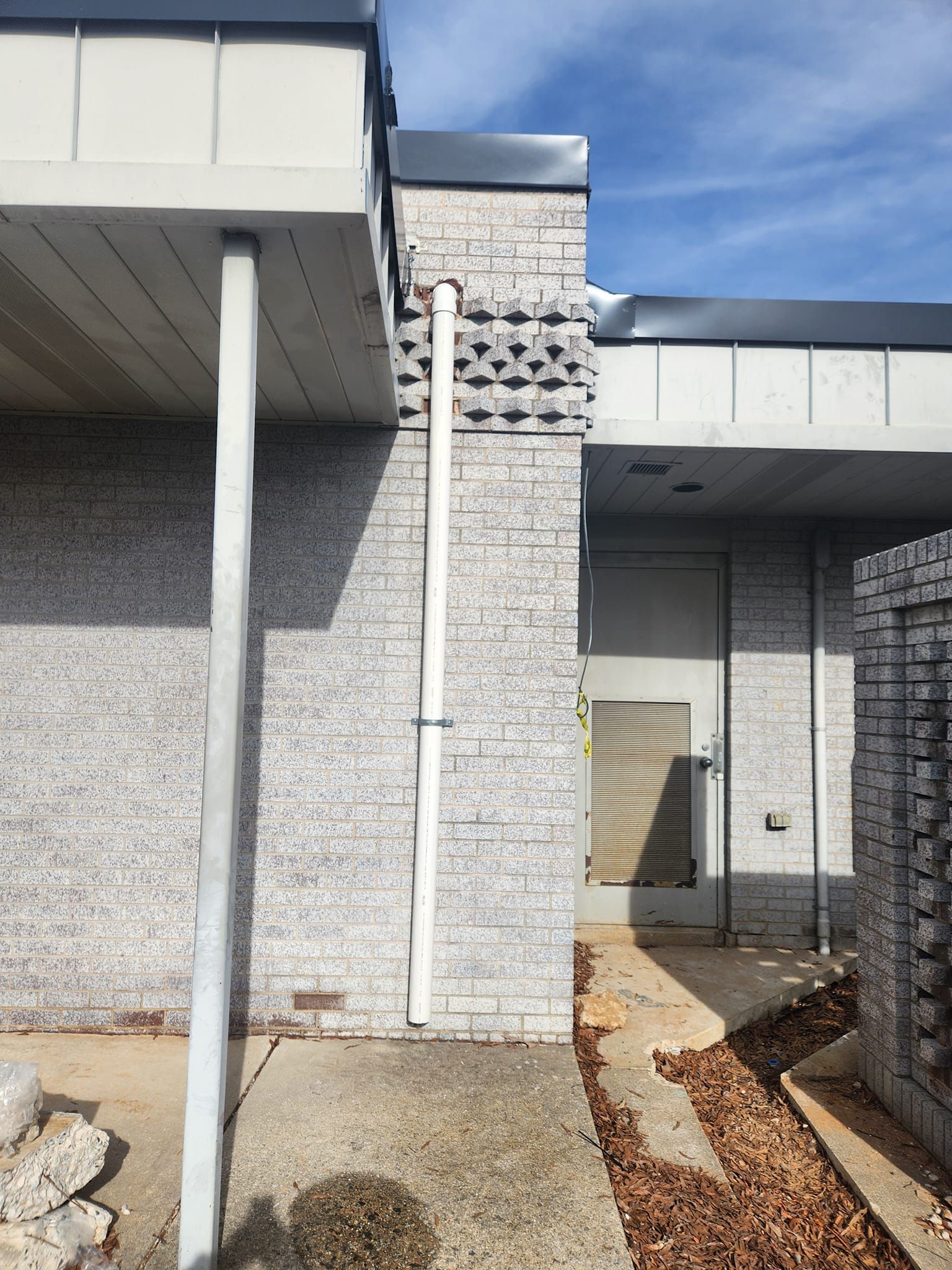 Exterior building with white and gray brick, gray metal beams, and a white downspout.