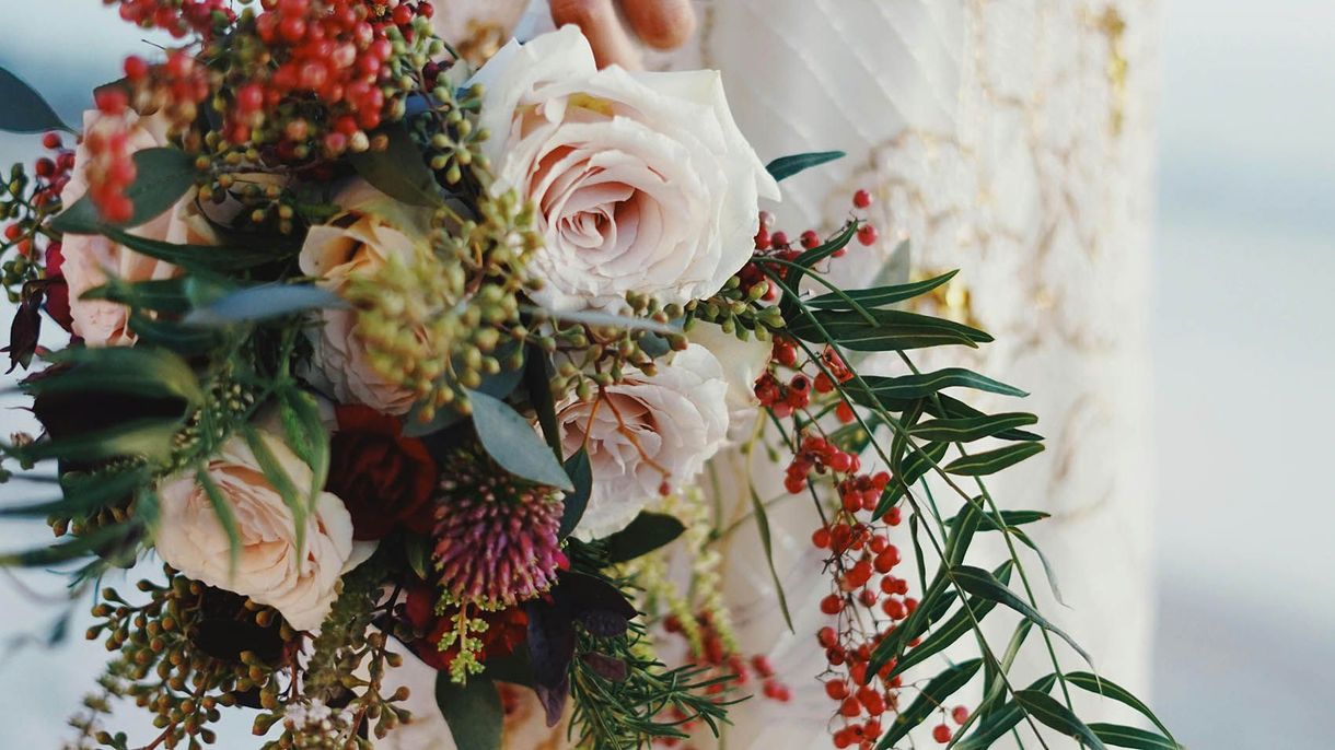 A bride is holding a bouquet of flowers in her hand.