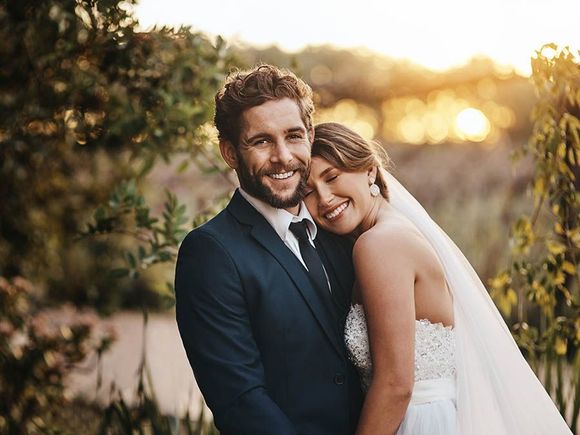 A bride and groom are posing for a picture on their wedding day.