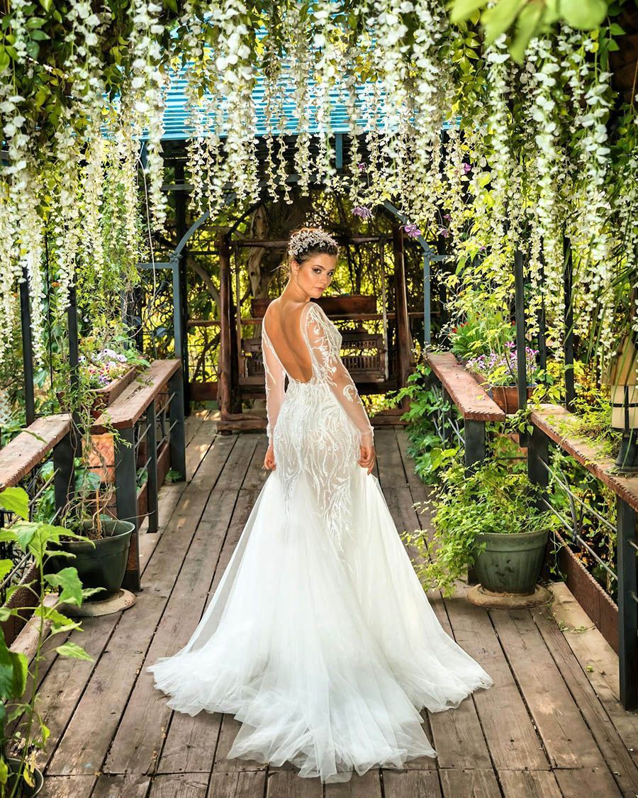 A woman in a wedding dress is standing on a wooden bridge.