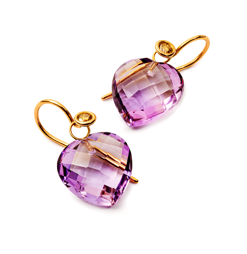 ein Paar lila herzförmige Ohrringe auf weißem Hintergrund