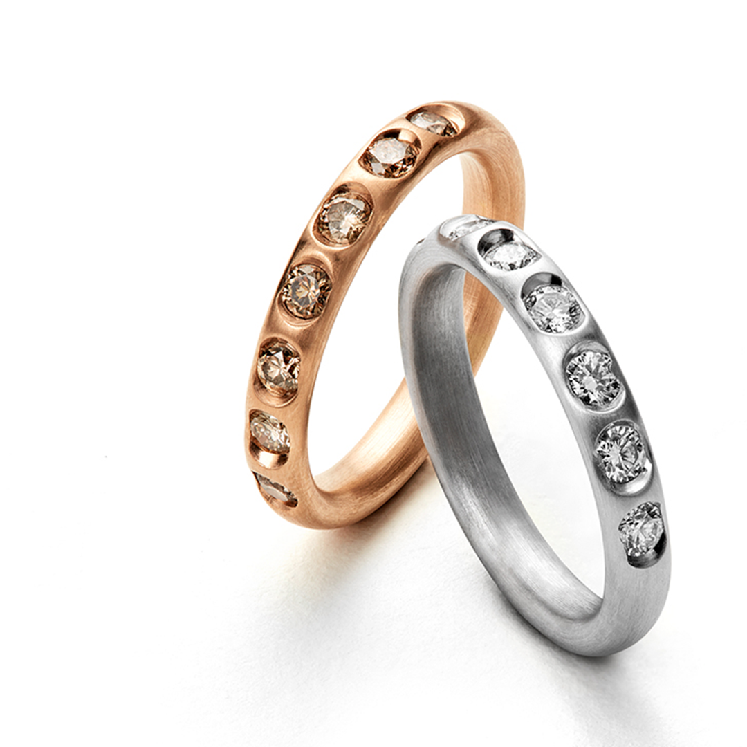 Zwei Ringe sitzen nebeneinander auf einer weißen Fläche