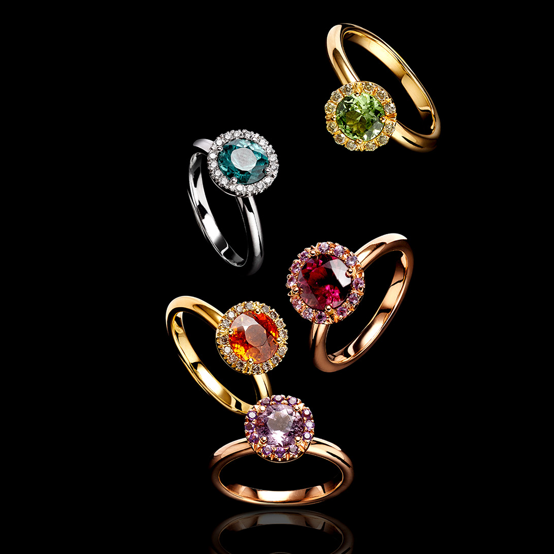 eine Gruppe von Ringen mit verschiedenfarbigen Steinen auf schwarzem Hintergrund