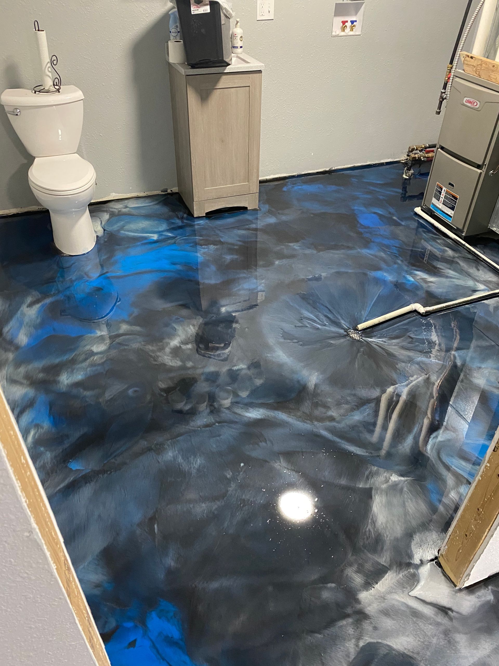 A bathroom with a blue and gray metallic floor and a toilet.