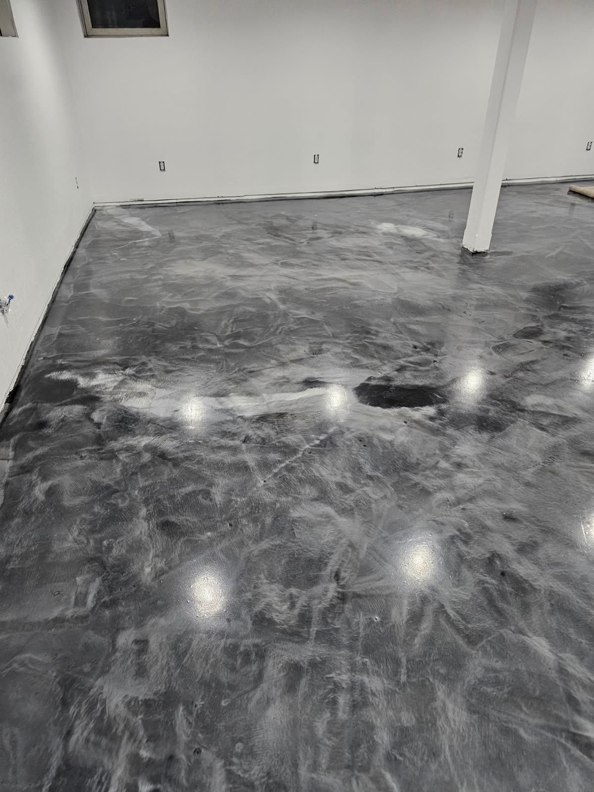 A black and white photo of a shiny metallic floor in a basement.
