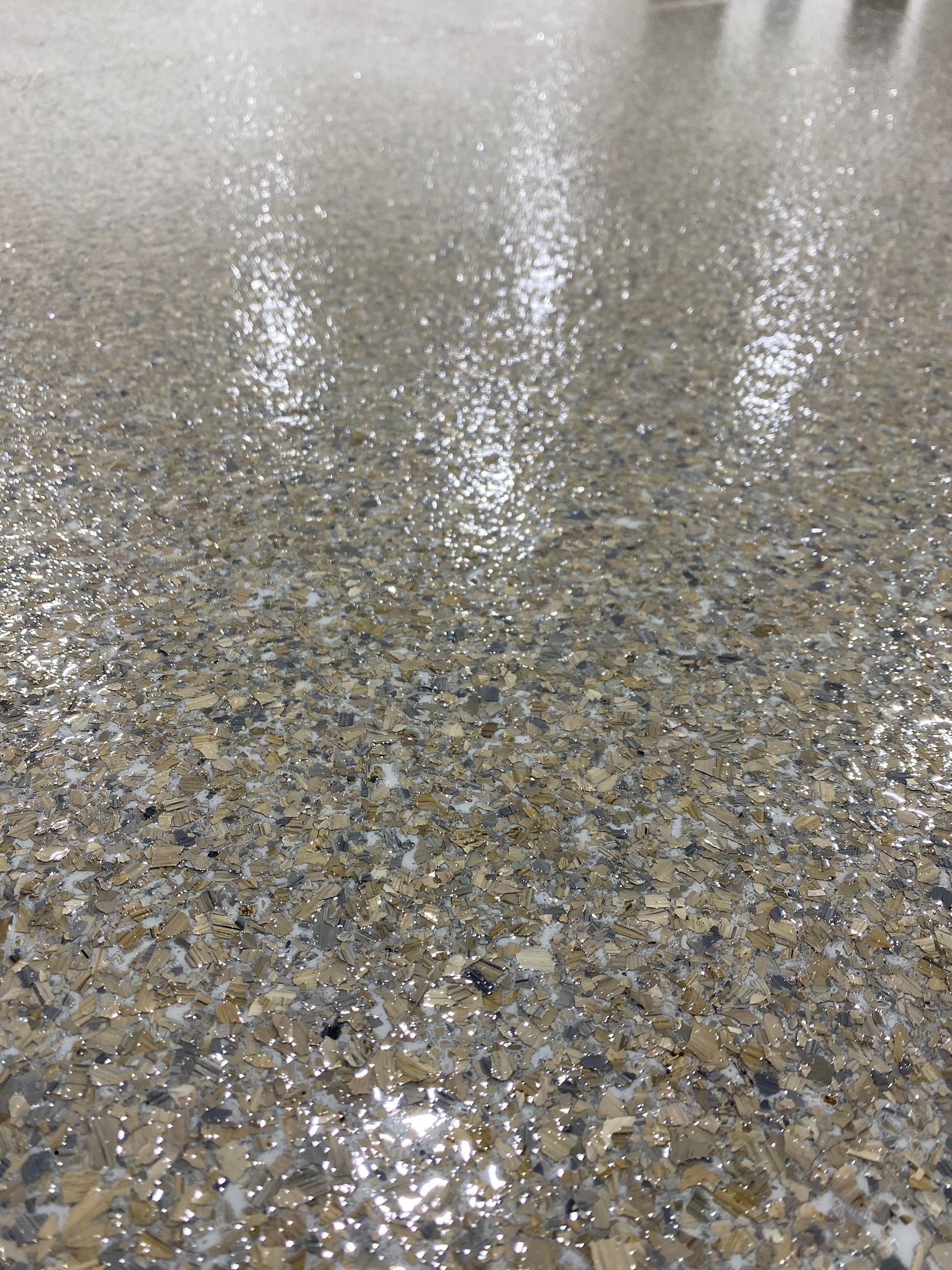 A close up of a shiny concrete floor with a lot of small rocks on it.