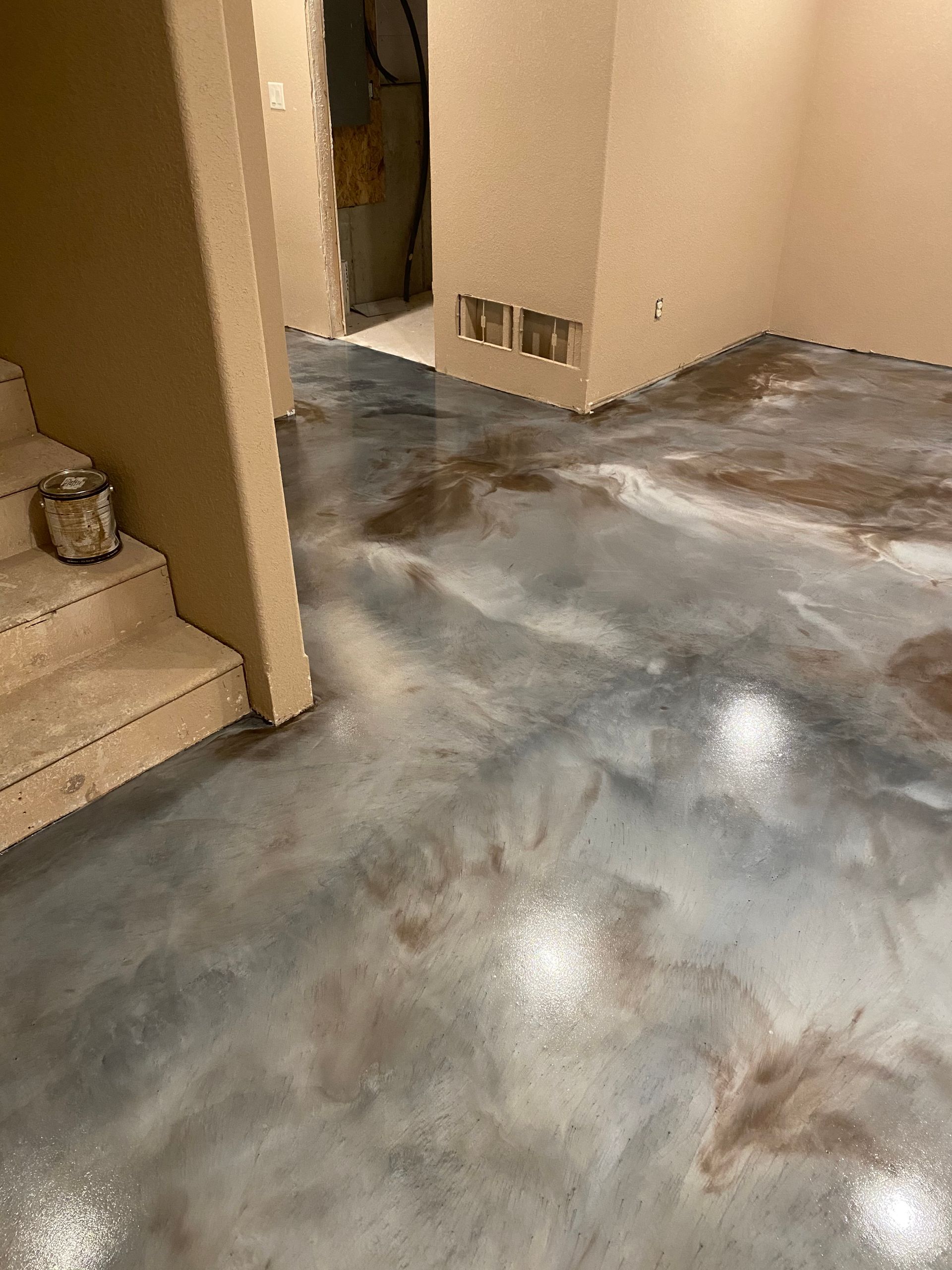 A basement with a metallic floor and stairs.
