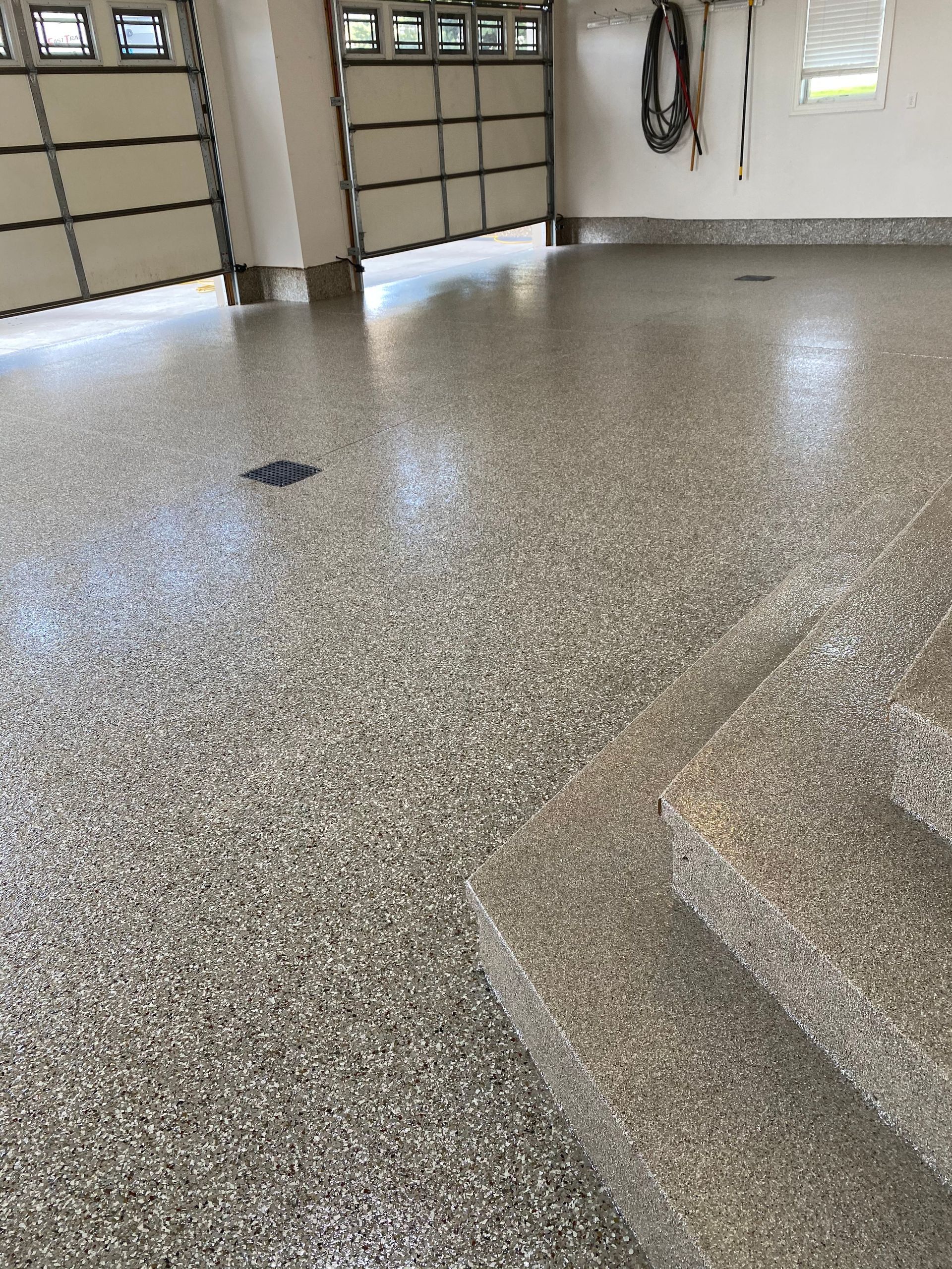 A garage with a concrete floor and stairs and a garage door.